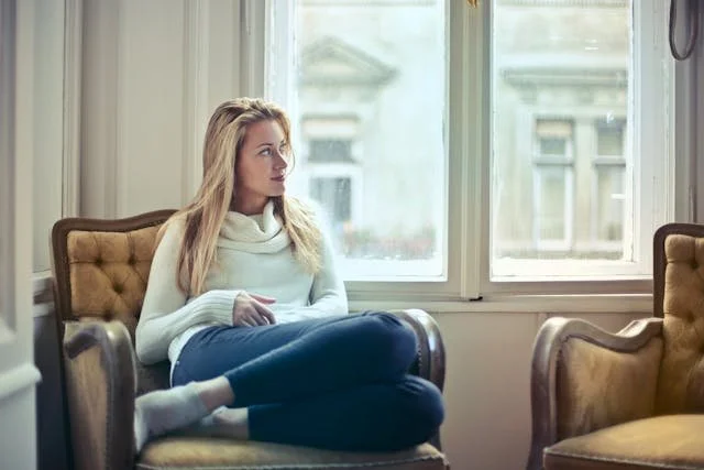 A woman sitting in a chair looking out the window