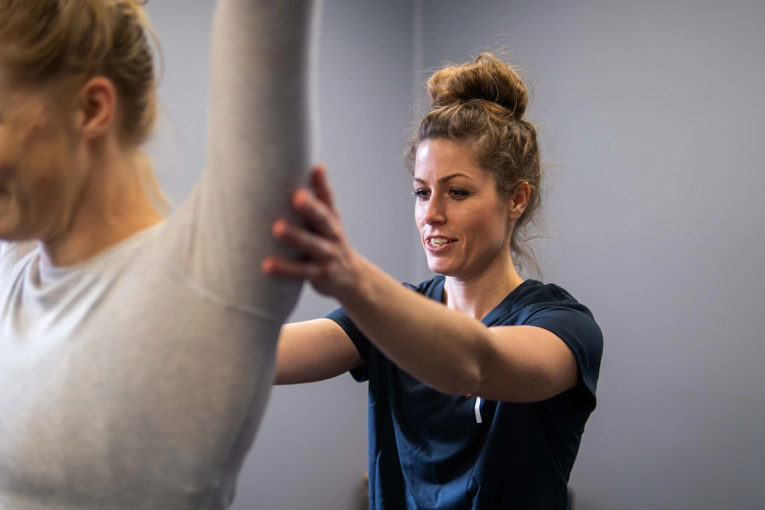 Fitness trainer assisting a woman with stretchingExercises in a gym.