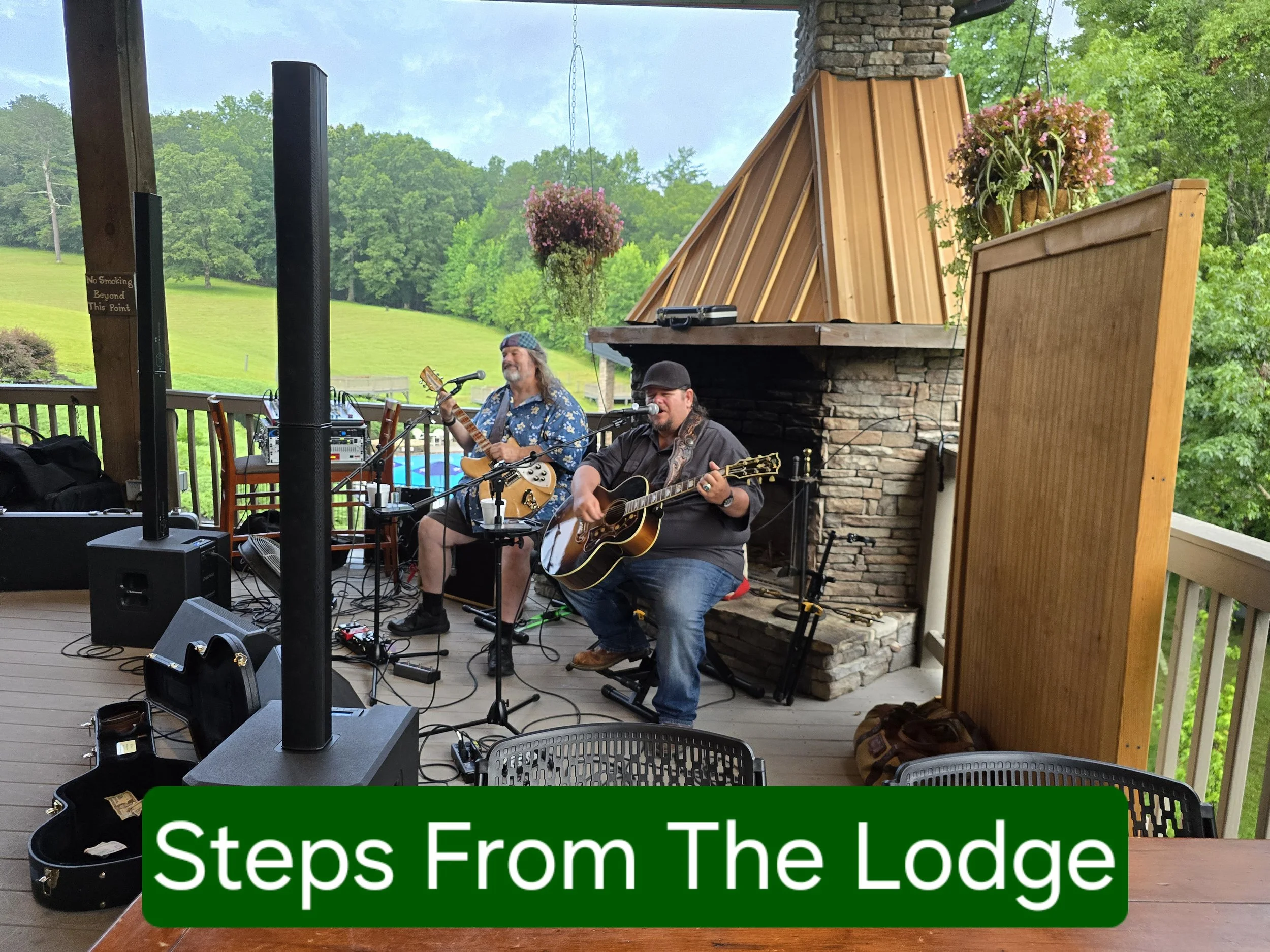 Best entertainent venue blairsville, ga. Live music blairsville, ga Two musicians playing guitars on a covered outdoor stage with green trees and a landscape in the background, also includes a microphone setup and speakers.