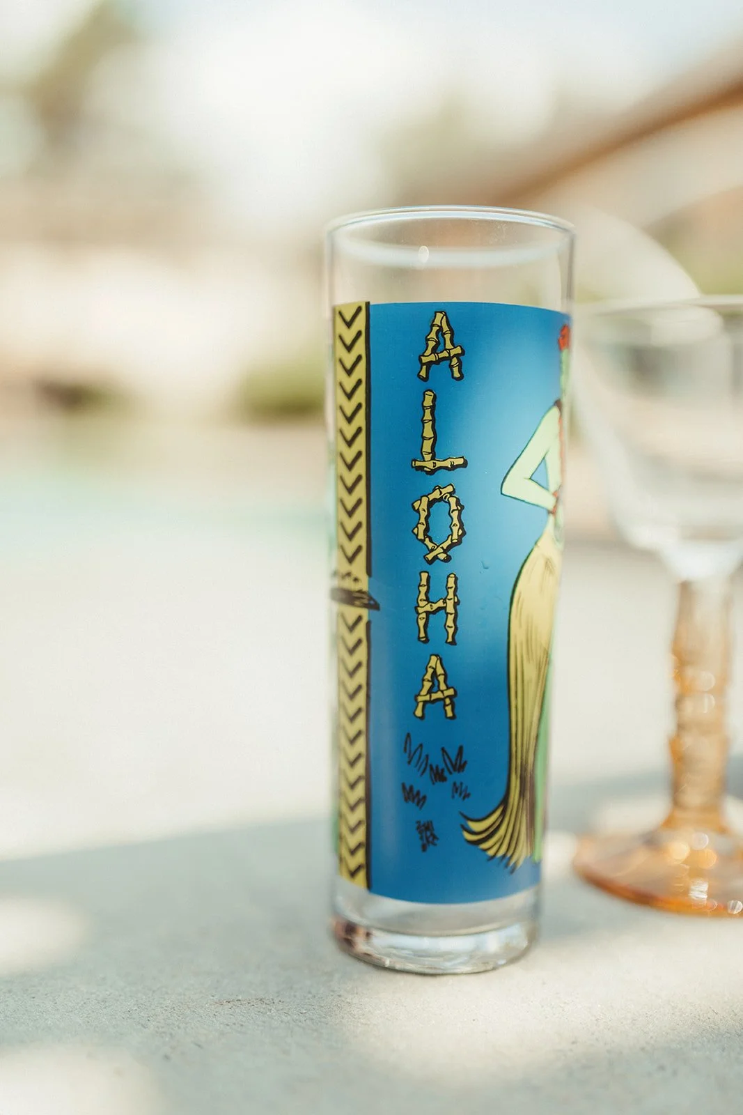 A tall glass with a colorful illustration and the word 'ALOHA' in yellow letters.