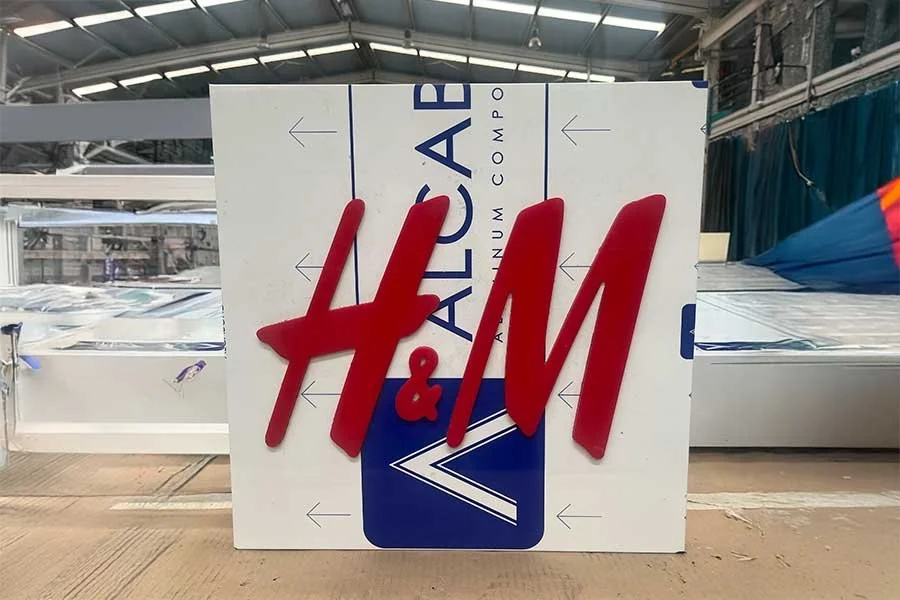 Cartel de H&M con la publicidad de Alucobond en un espacio de fábrica.