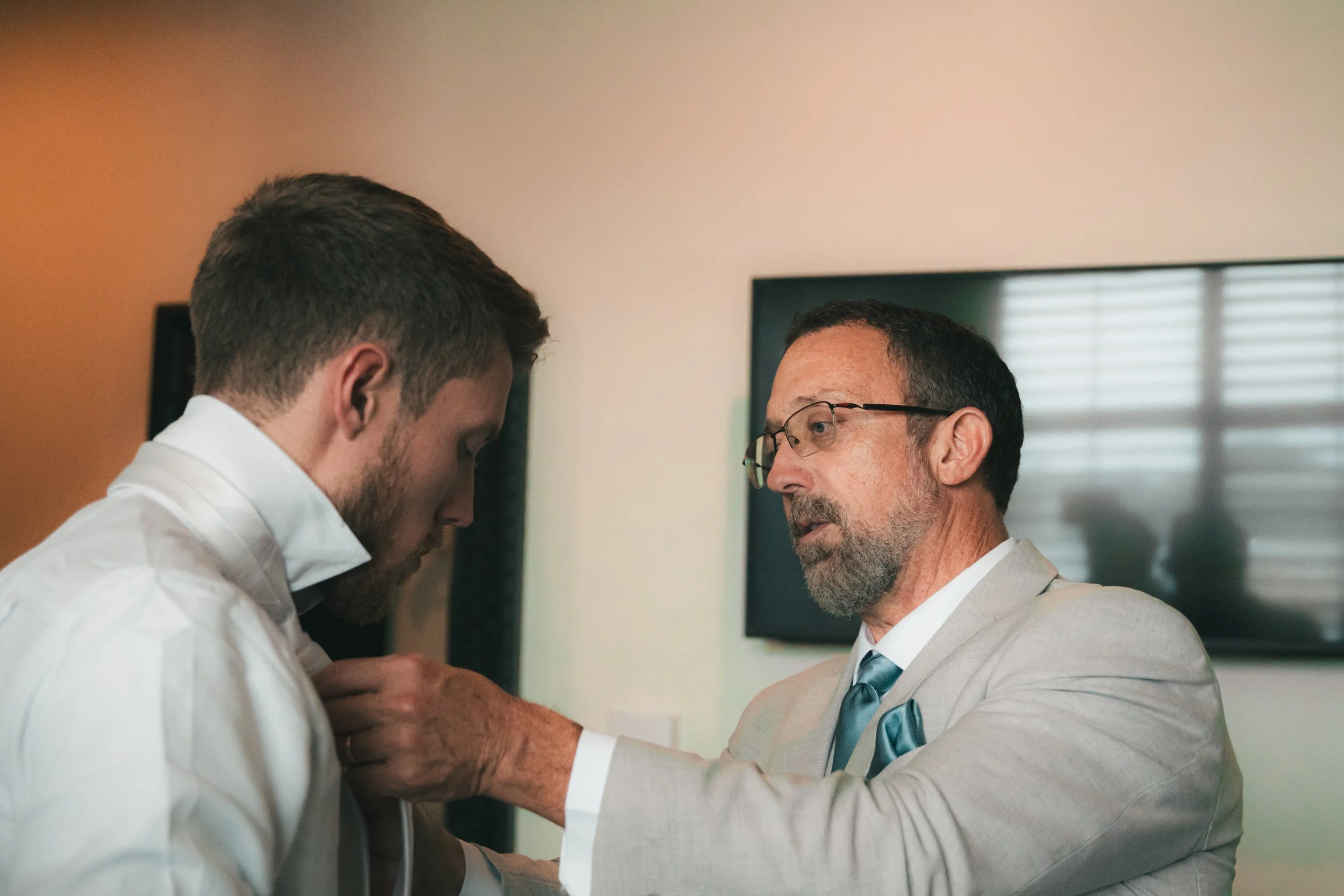A young man and an older man in suits are engaged in a close, serious conversation in a professional setting.