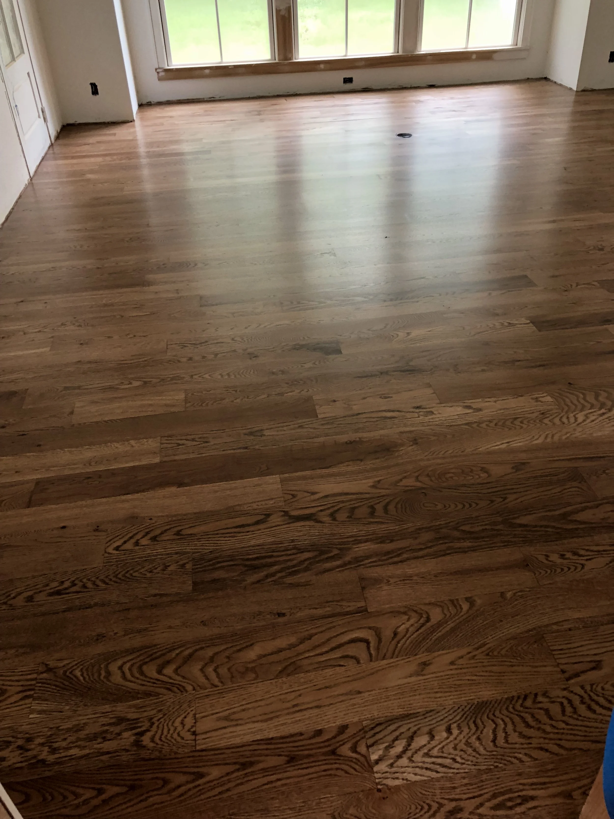 Empty room with wooden floor and large windows.