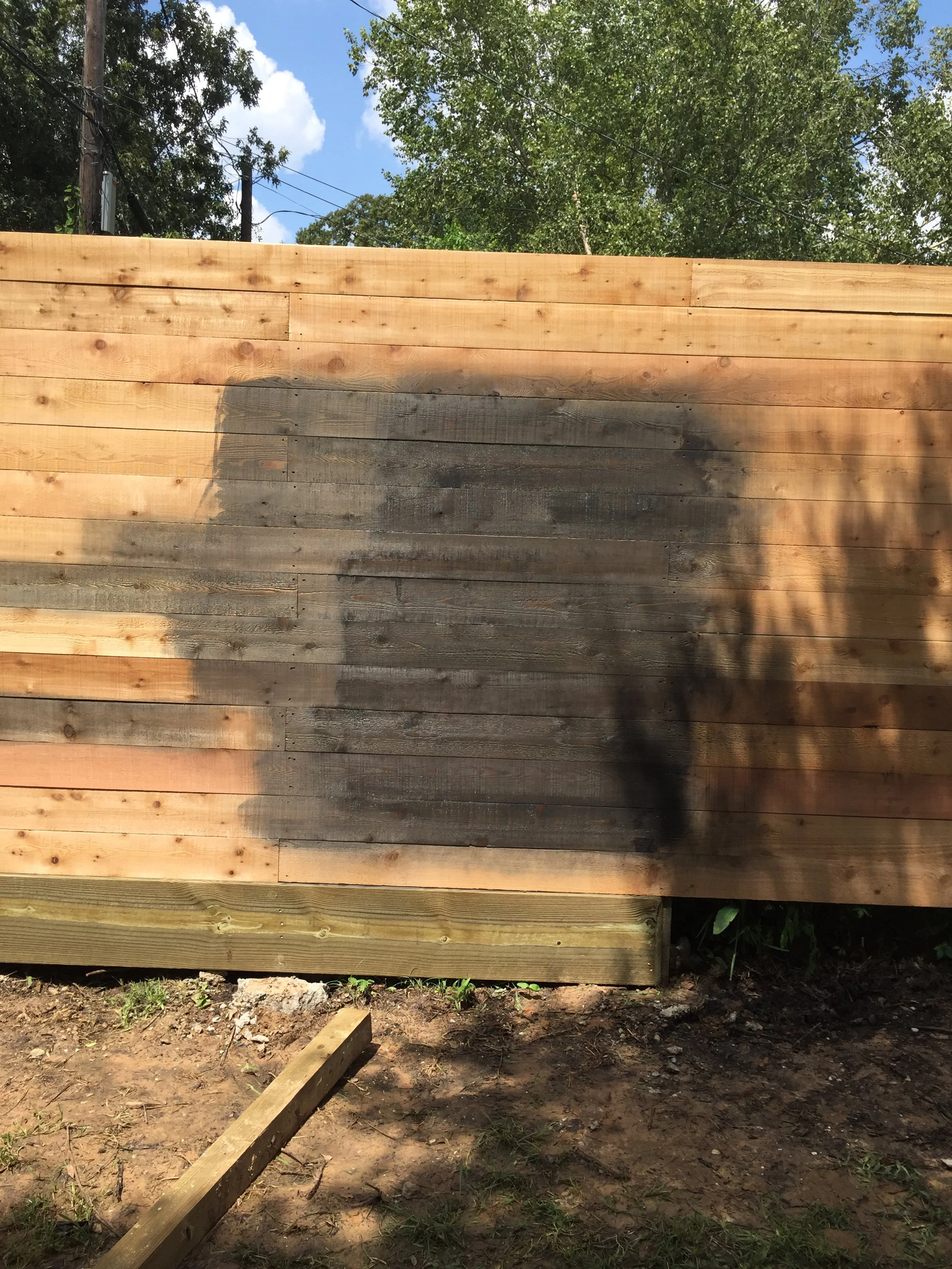 Wooden fence with partially darker stained section