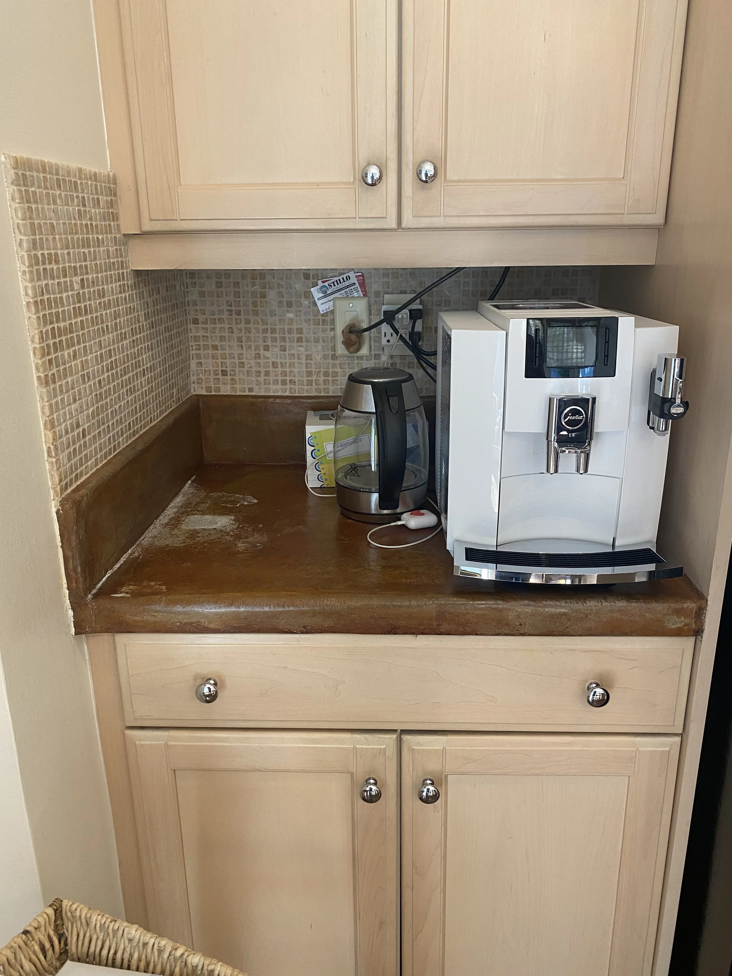 Kitchen countertop with coffee machine, electric kettle, and cabinets