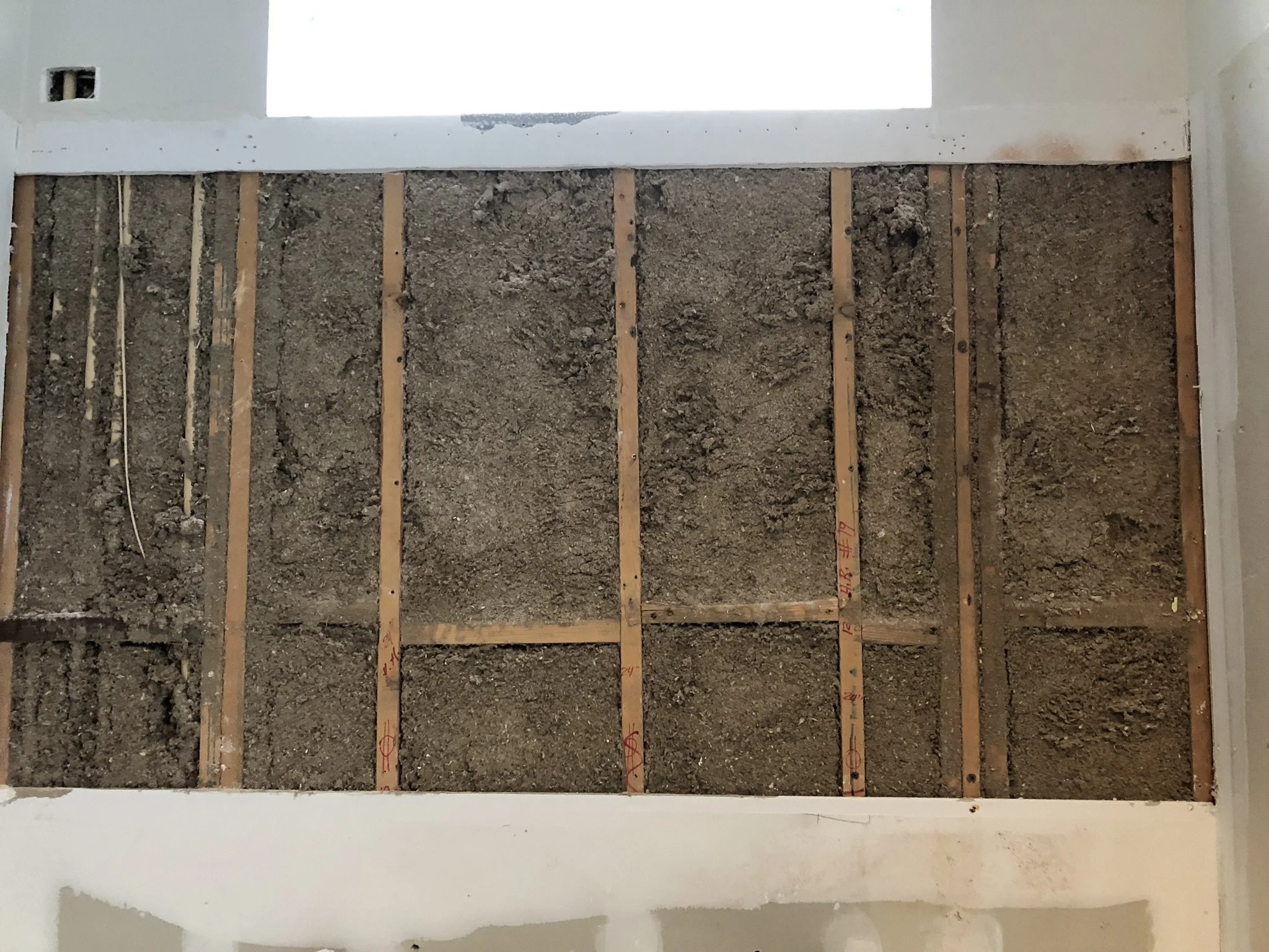 Exposed interior wall with wooden studs and insulation, under renovation.
