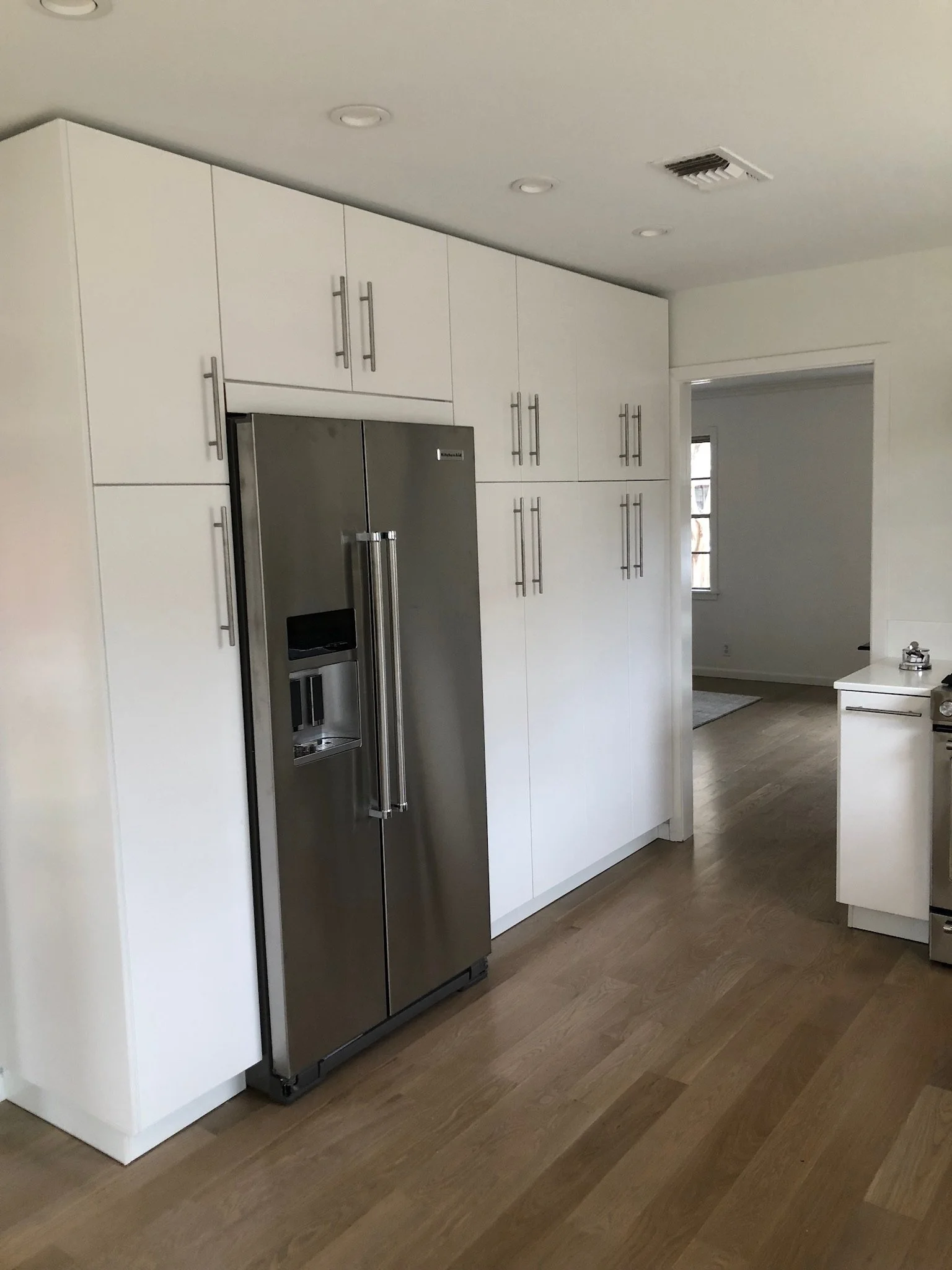 Modern kitchen with white cabinets and stainless steel refrigerator