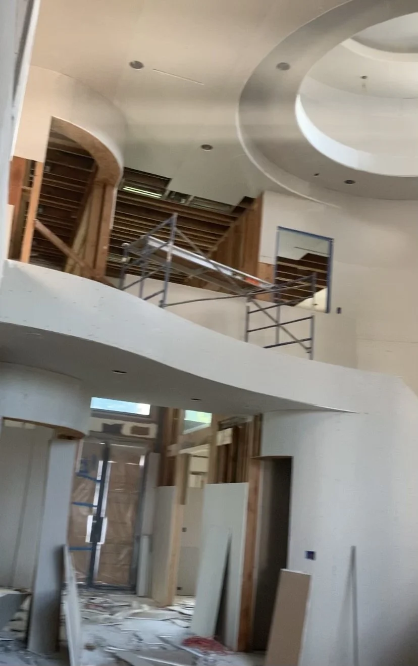 Interior of a building under construction with scaffolding, exposed framework, and unfinished walls.