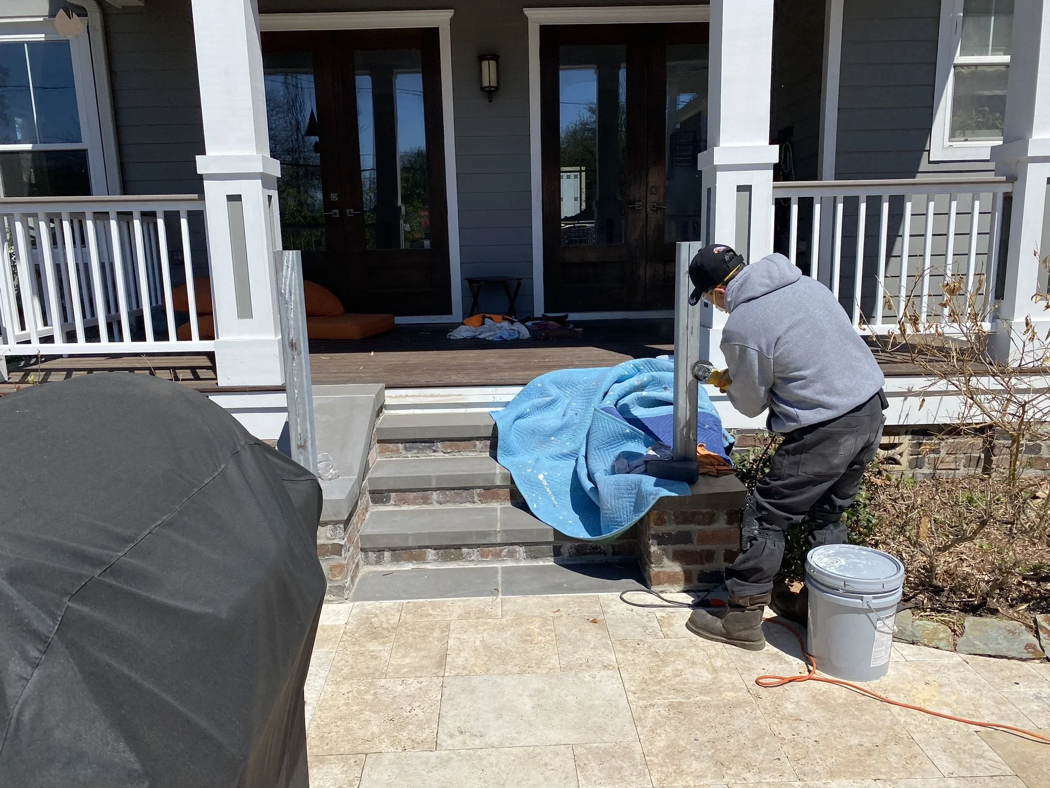 J. Luis Construction Inc worker is installing railing on front porch steps