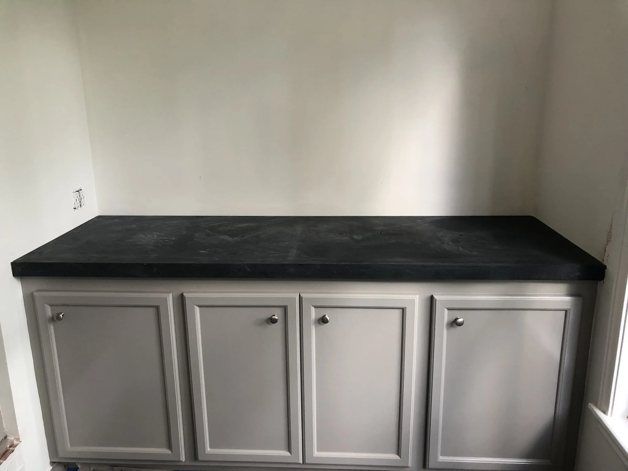Gray cabinet with black countertop in an empty room