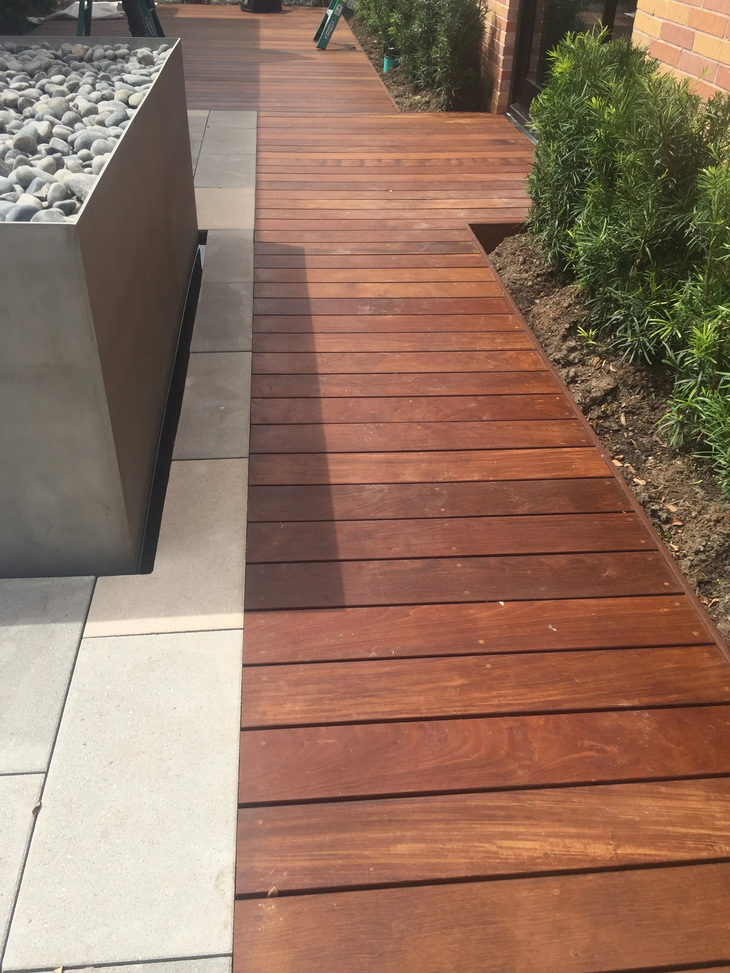 Wooden deck with adjacent garden beds and a stone planter