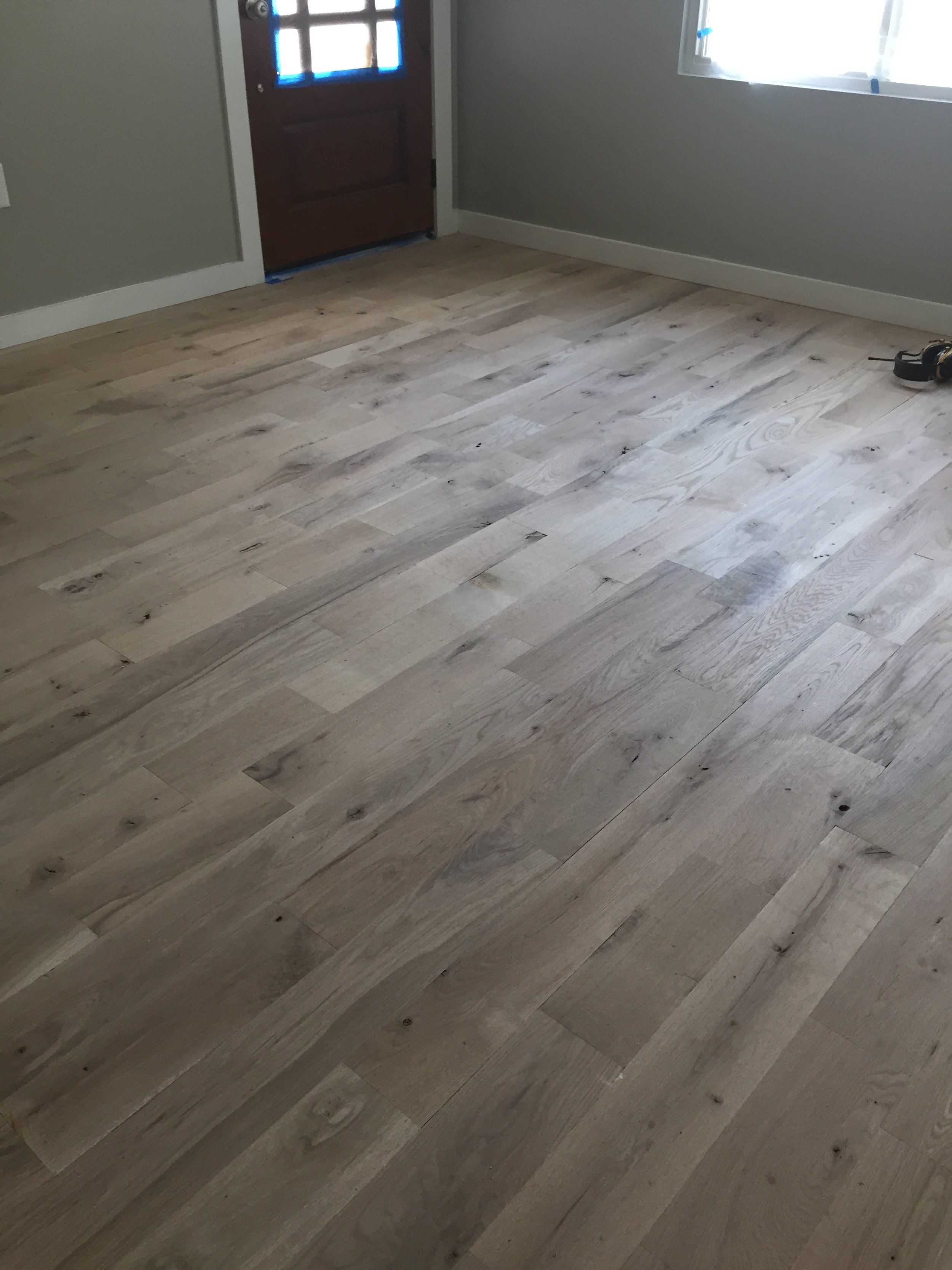 Room with light wood flooring and a partially visible brown door