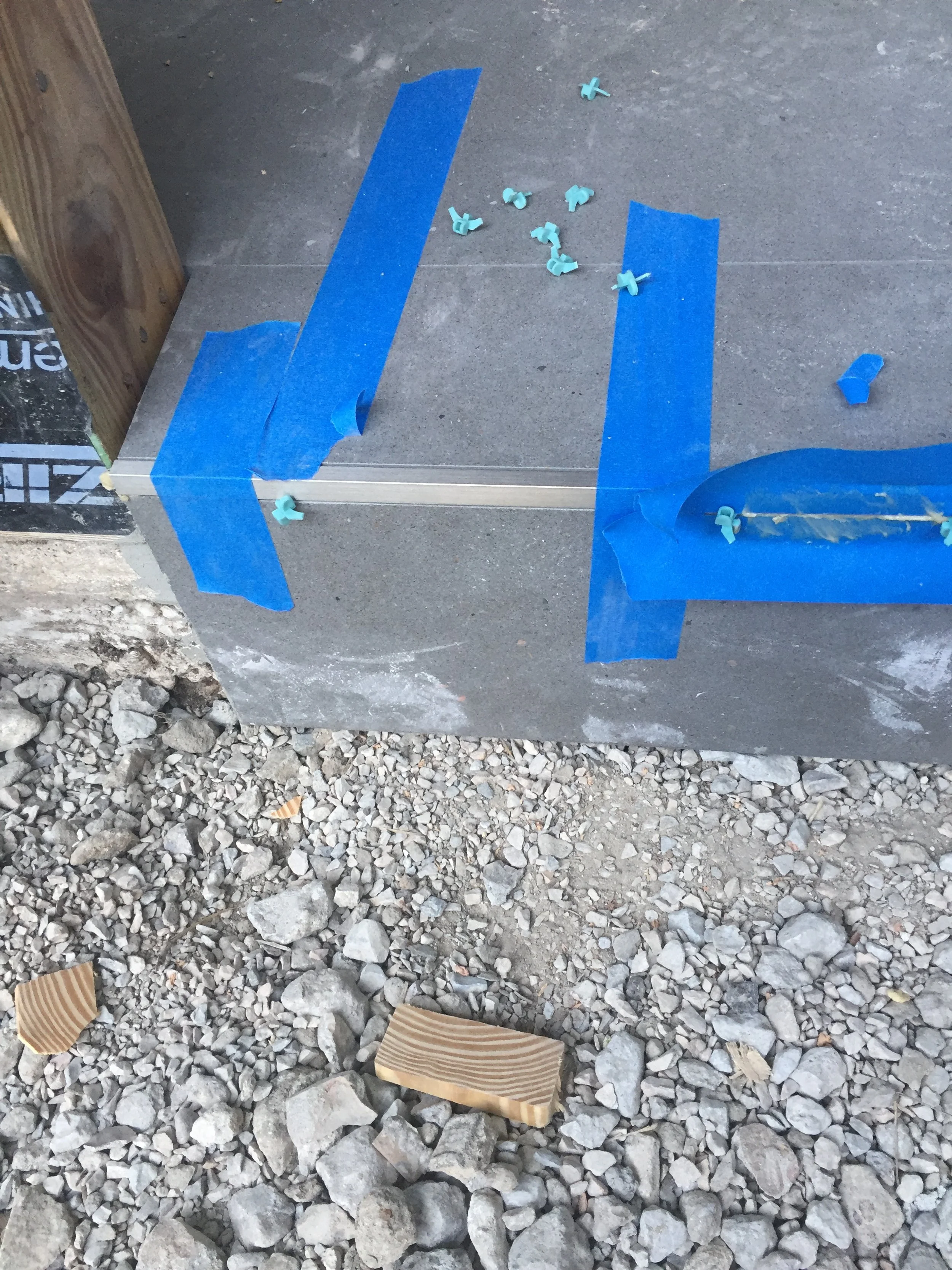 Concrete step with blue painter's tape and tile spacers