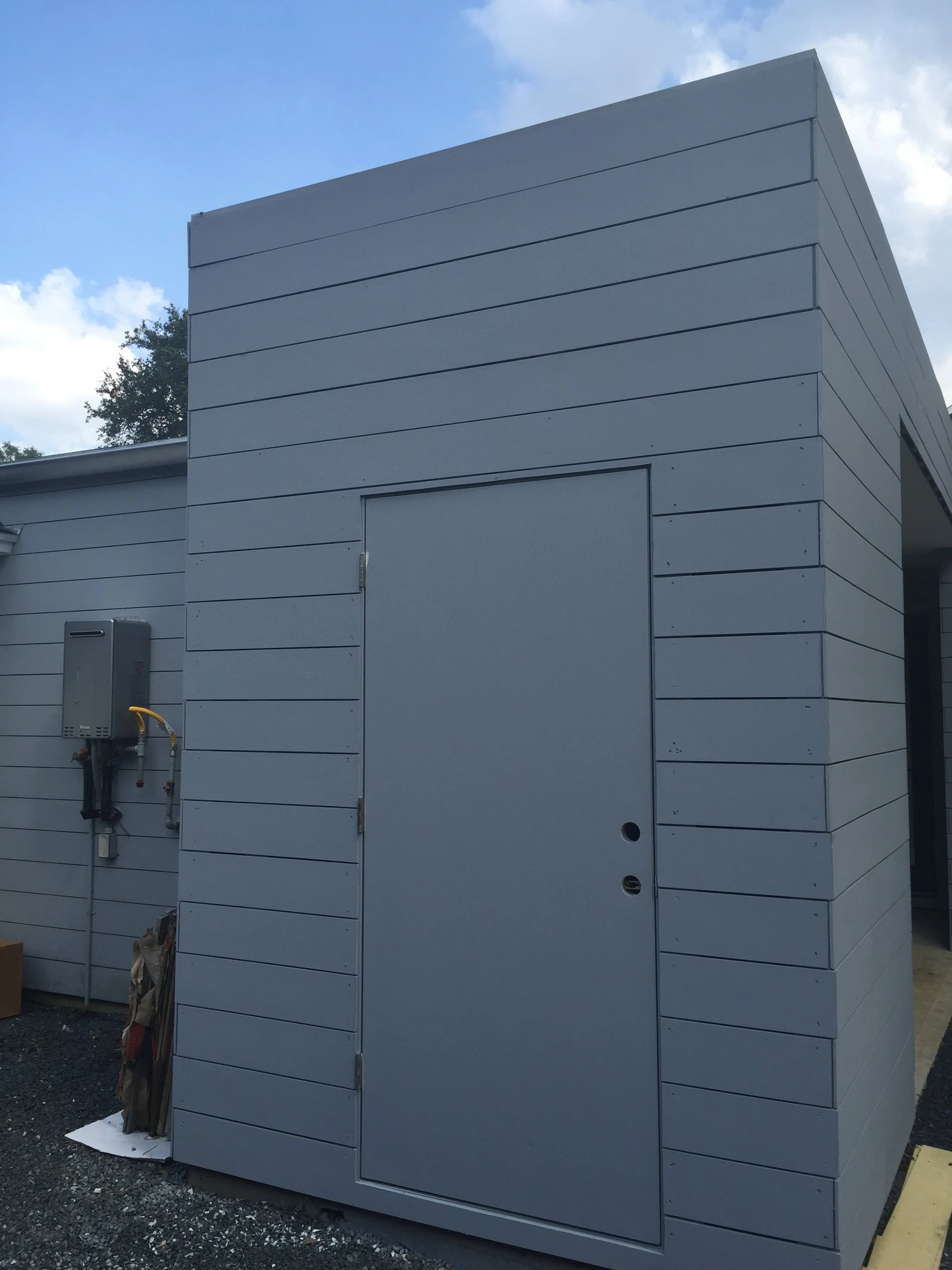 Gray utility shed with door and electrical panel