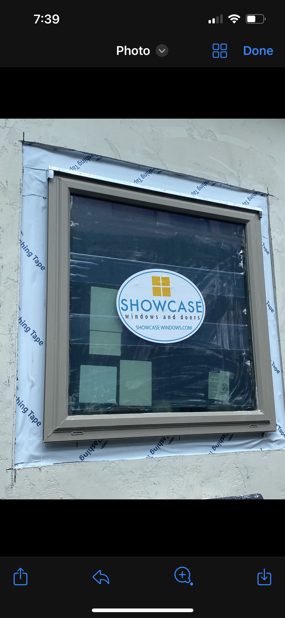 Window with sticker, Showcase Windows and Doors, brown frame, flashing tape visible.