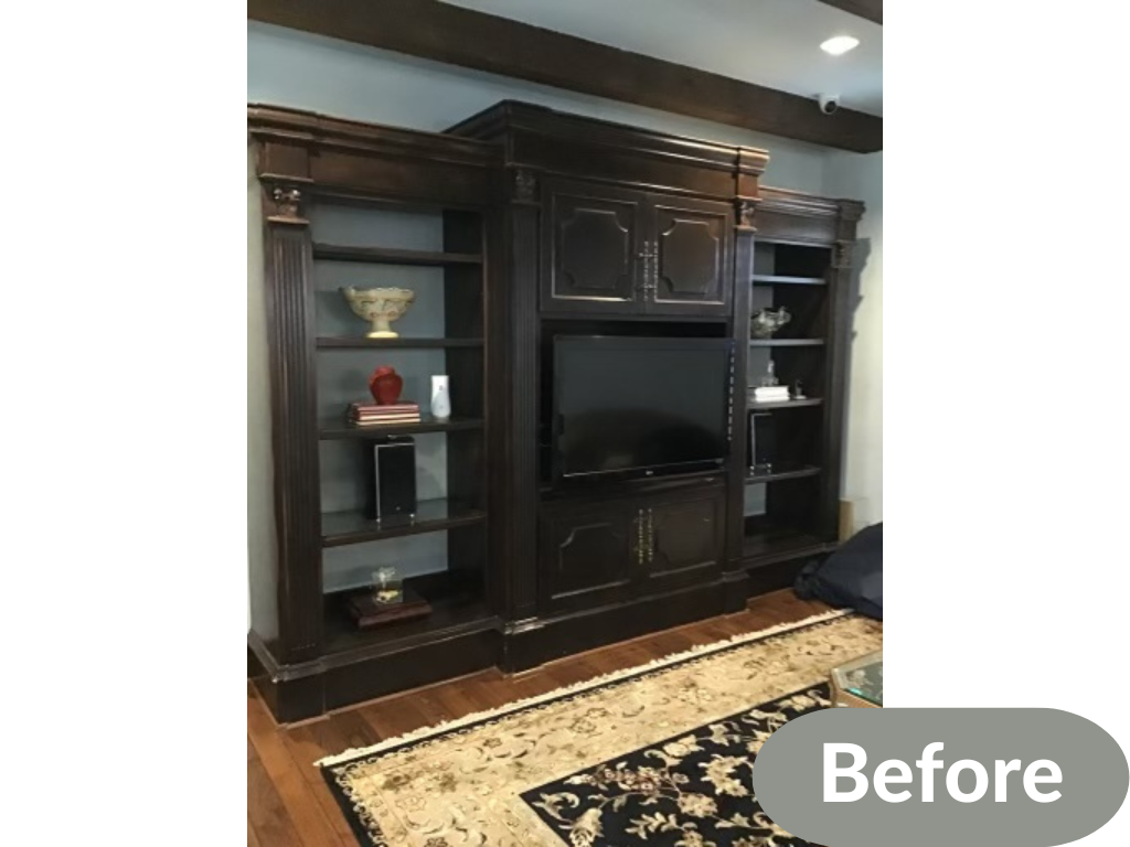 Dark wood entertainment center with shelves, TV, decorative items, and cabinets, before renovation.