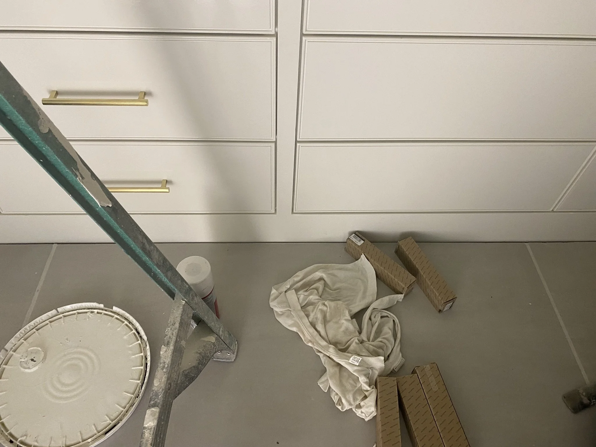 Ladder and paint supplies near white cabinets