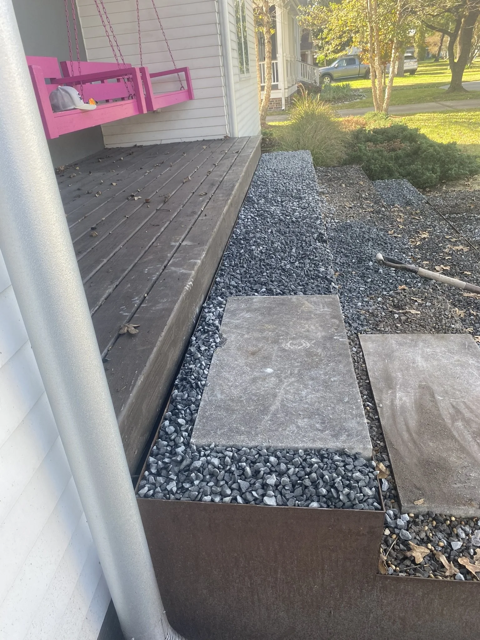 Porch with pink swing, gravel area, and stepping stones.