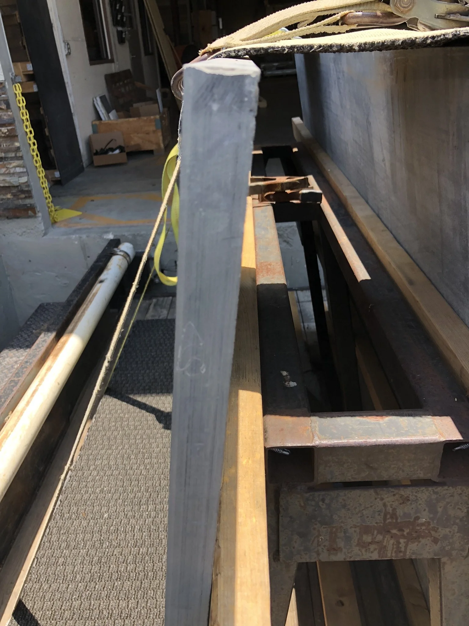 Close-up of a metal beam in a workshop setting with tools and materials in the background.
