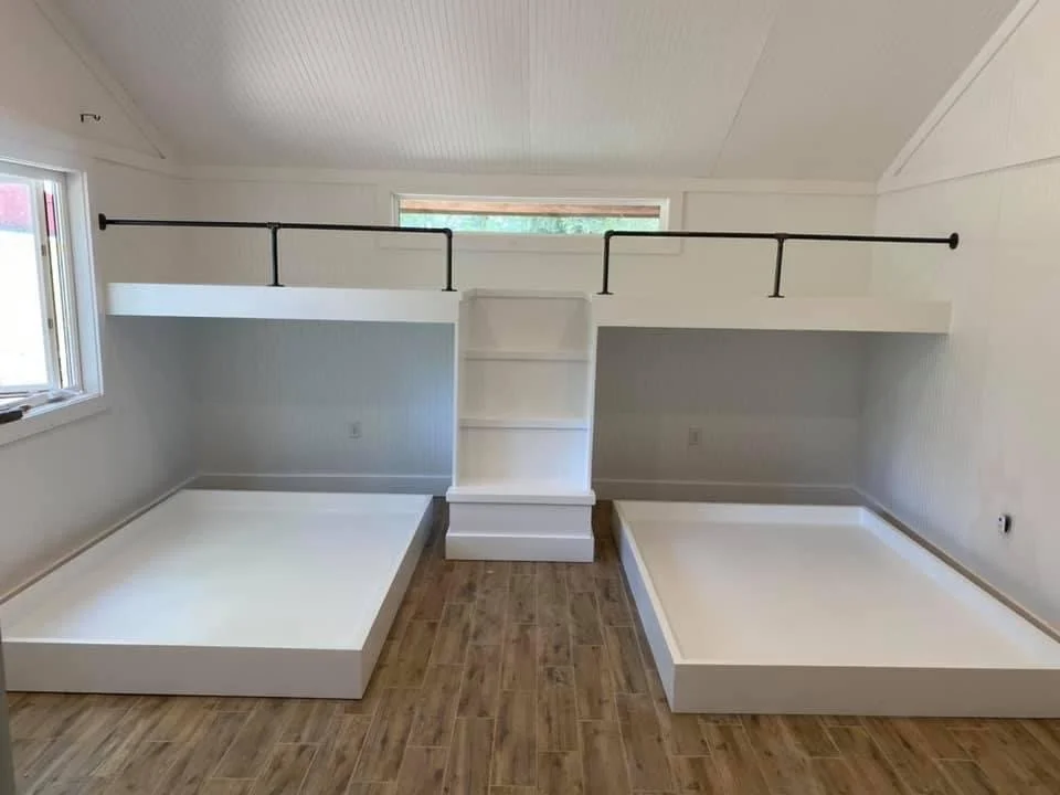 Room with two platforms, wooden floor, railing, and shelving in center wall.