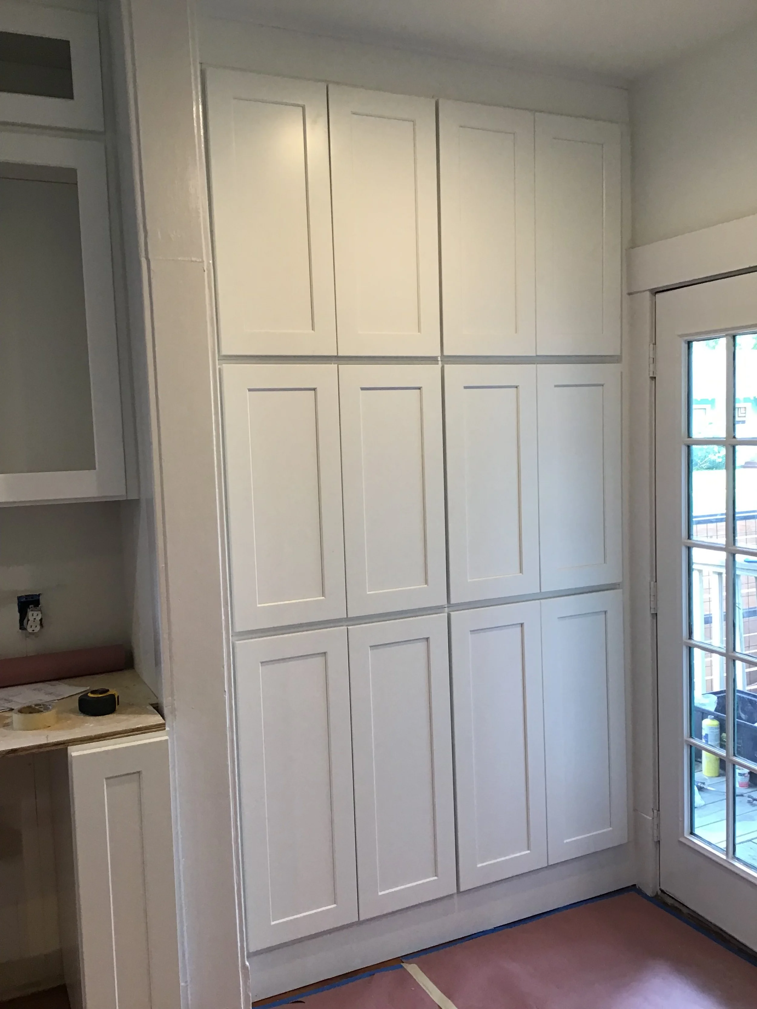 White kitchen cabinet with multiple doors next to sliding glass door