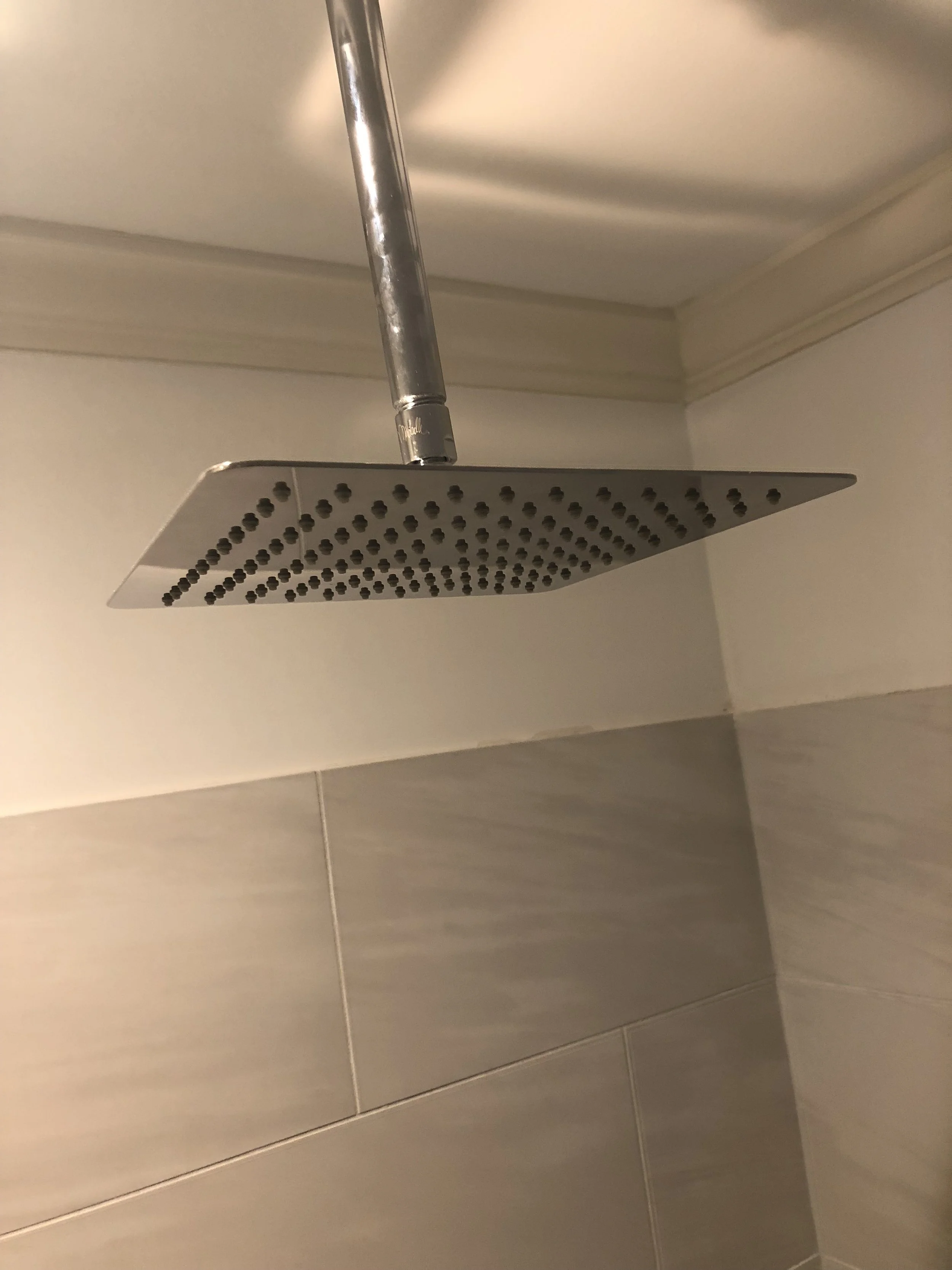 Ceiling-mounted square rainfall shower head in bathroom