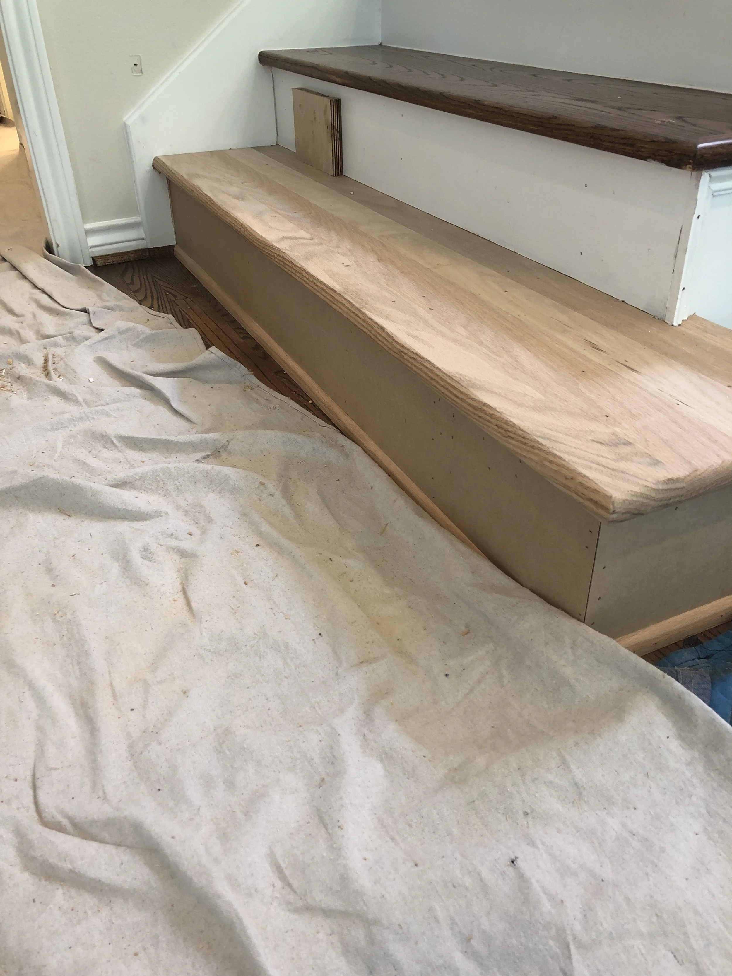 Home stair renovation with wooden steps, drop cloth on floor.