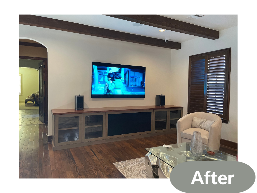Living room setup with wall-mounted TV, wooden cabinet, speakers, white armchair, and a glass coffee table. Hardwood floors and wooden ceiling beams are visible, along with a window with shutters. Labeled 'After' in the corner.
