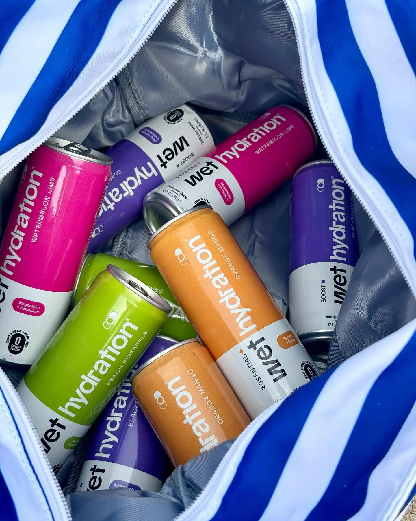 Inside a bag, there are several cans of Wet Hydration+ water, including flavors such as watermelon, orange, peach pineapple, and blackcurrant.