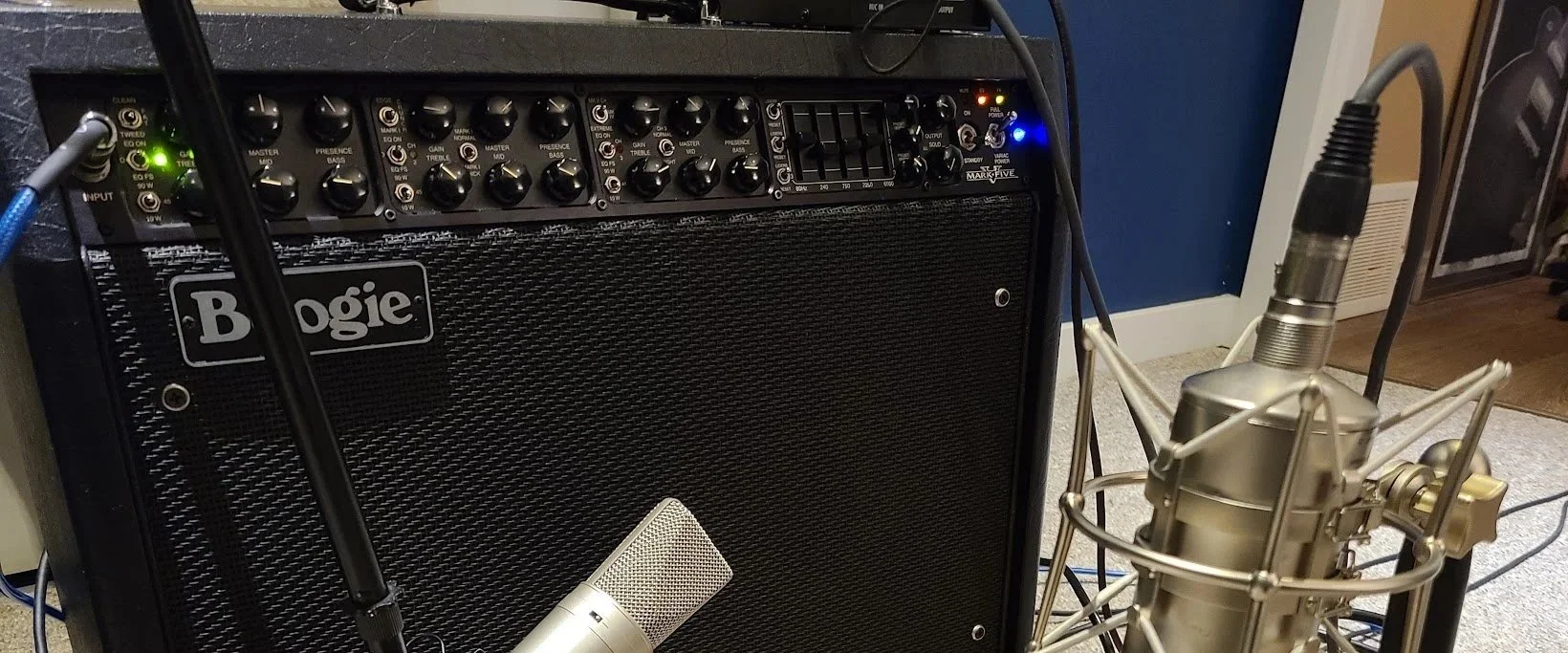A Boggie guitar amplifier is shown with a large condenser microphone in front of it, connected with cables, in a recording studio or music setup.