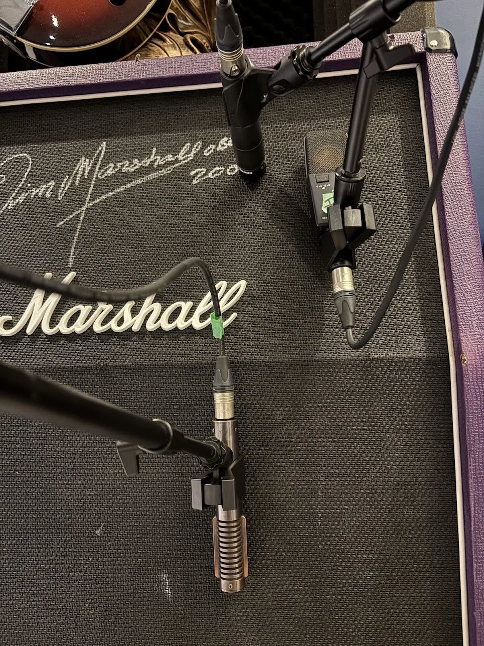Close-up of a Marshall amplifier with microphone stands and microphones set up in front of it.