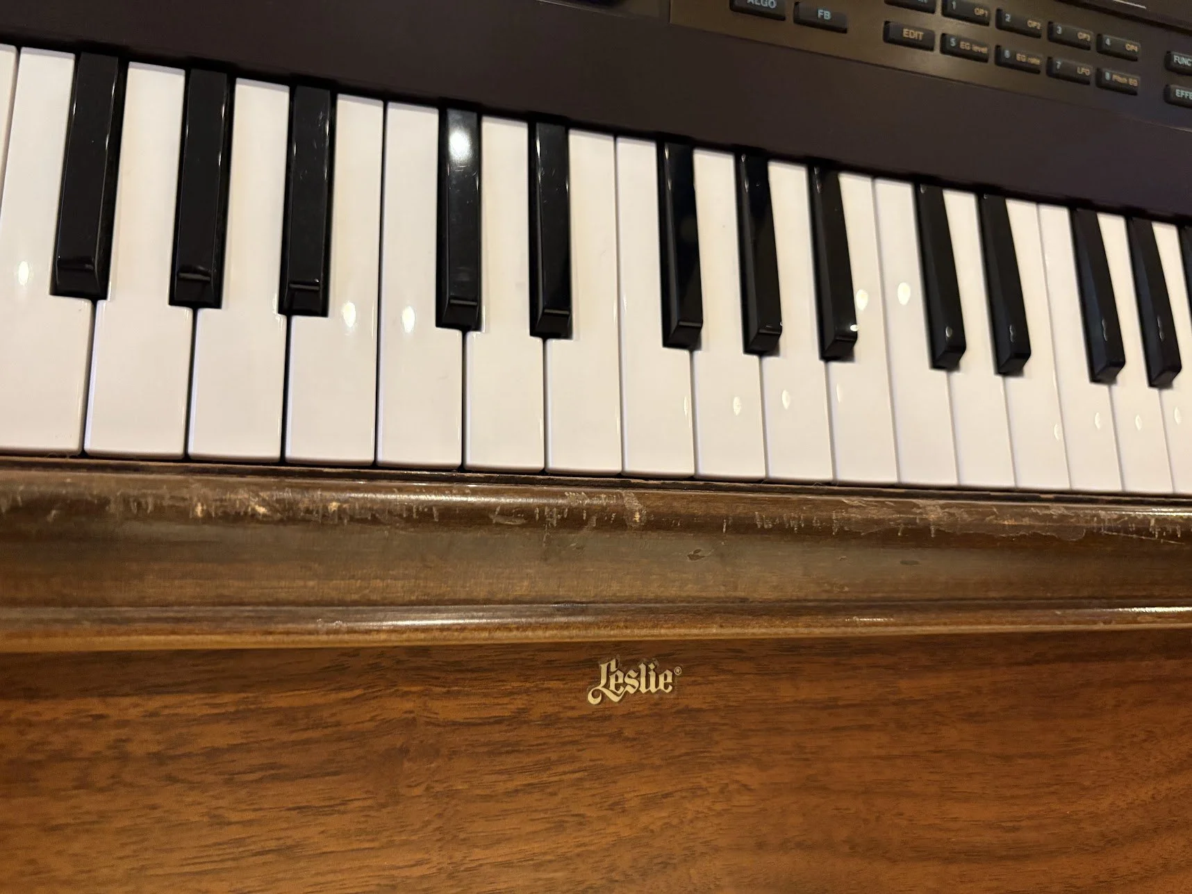 Top view of a Leslie electric organ keyboard with black and white keys, set in a wooden cabinet.