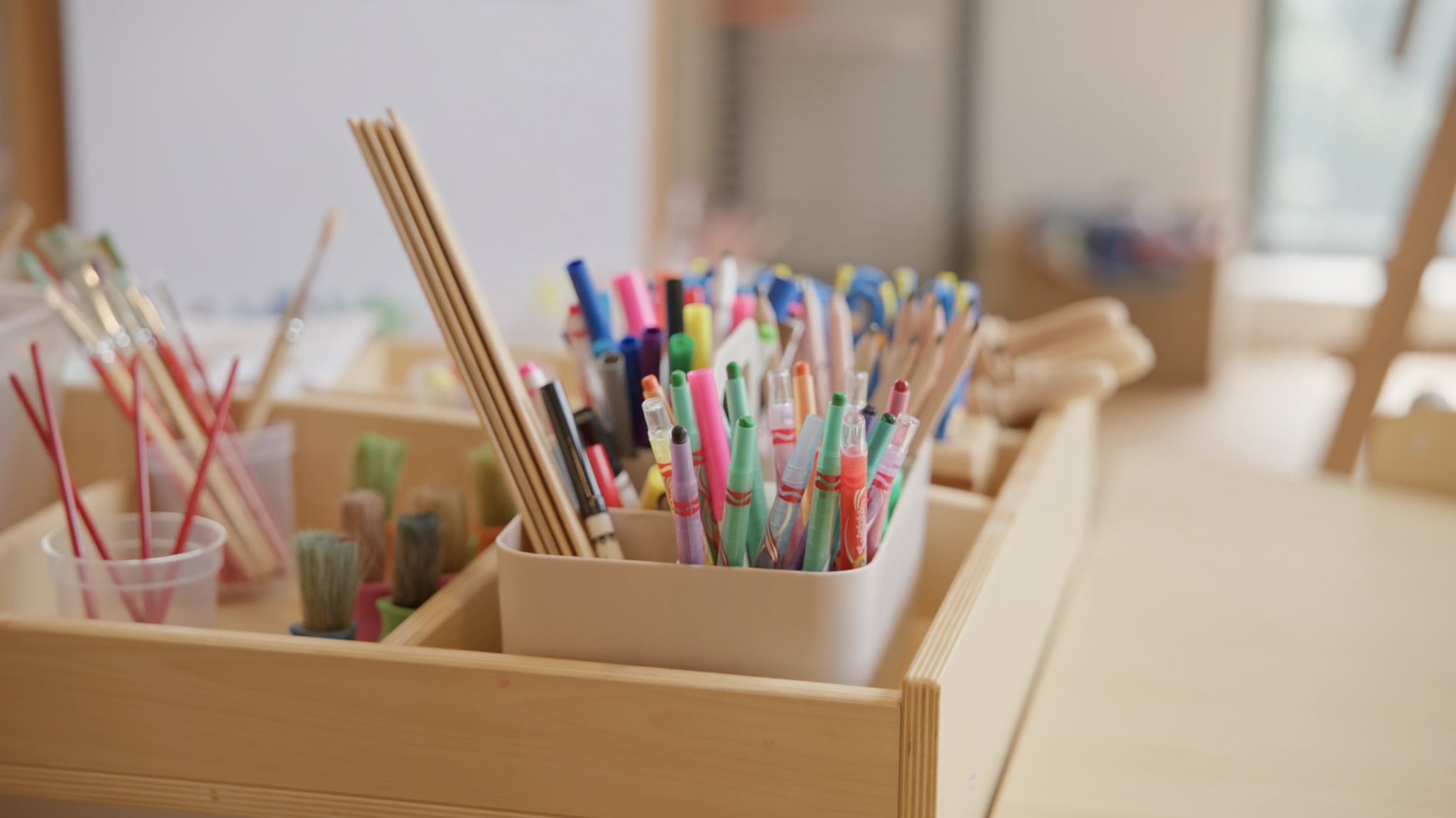 Collection of colorful pens and brushes in wooden organiser on a desk. Shot for a brand film by Talon Media in Brisbane for Edge Early Learning.