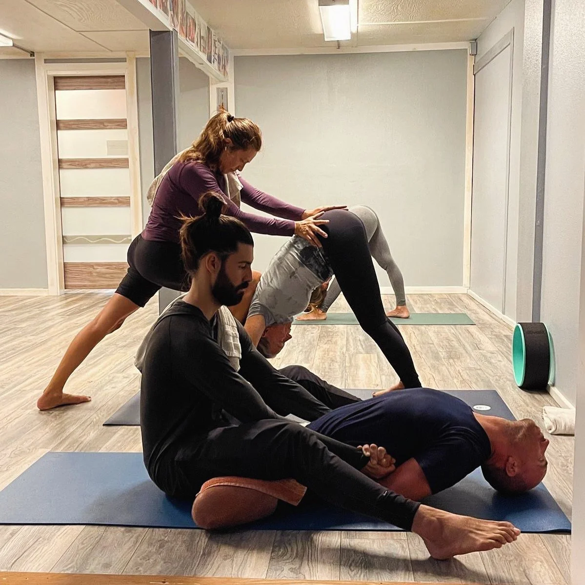 Christina Martini and Caio Amaral assisting students in Ashtanga Yoga postures