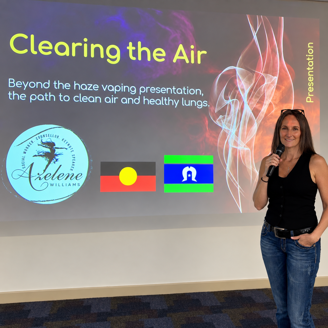  Azelene Williams holding a microphone stands in front of a presentation slide titled "Clearing the Air." The slide features text about cleaning air and healthy lungs.