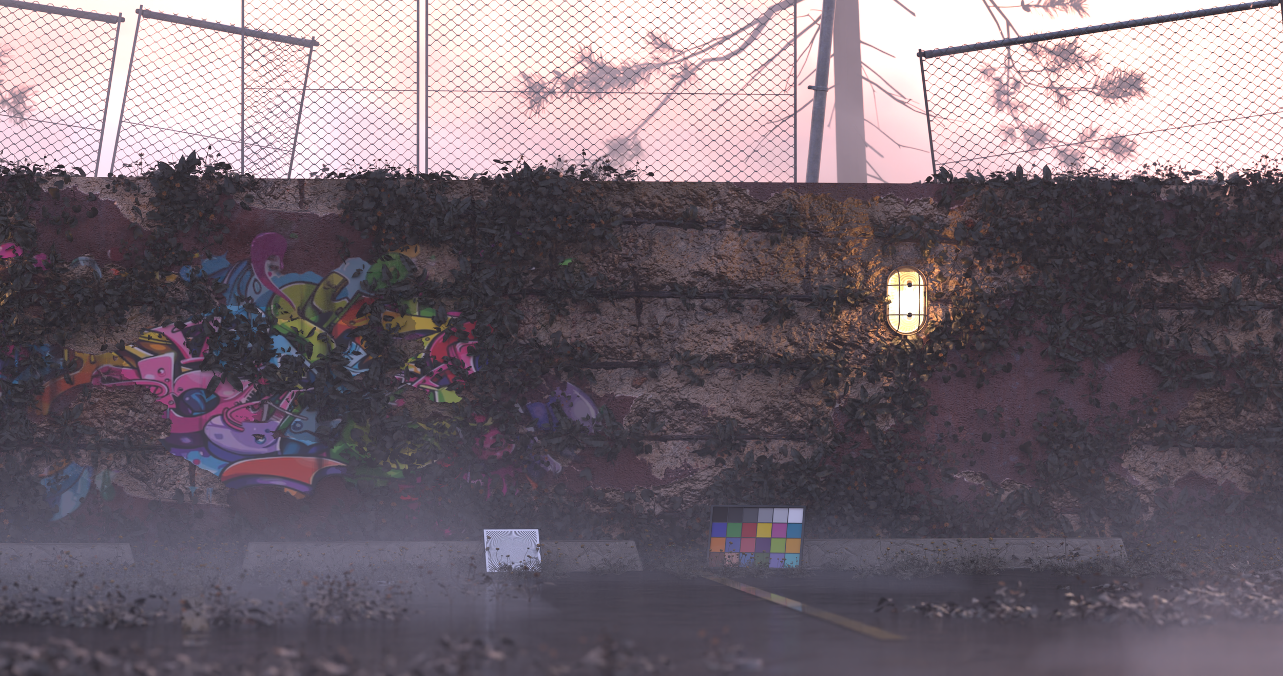 A graffiti mural on a concrete wall with a pink and purple sunset sky in the background, enclosed by a chain-link fence with grass and trees beyond. There are small measurement and color calibration charts on the ground in front of the wall.
