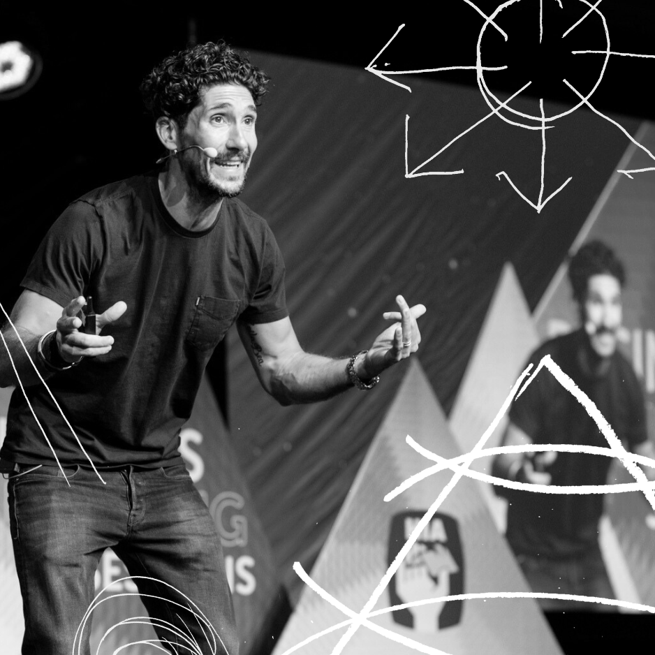 Gus Balbontin speaking on stage at a keynote, wearing a headset mic and gesturing mid-sentence, black and white photo with hand-drawn doodle graphics.