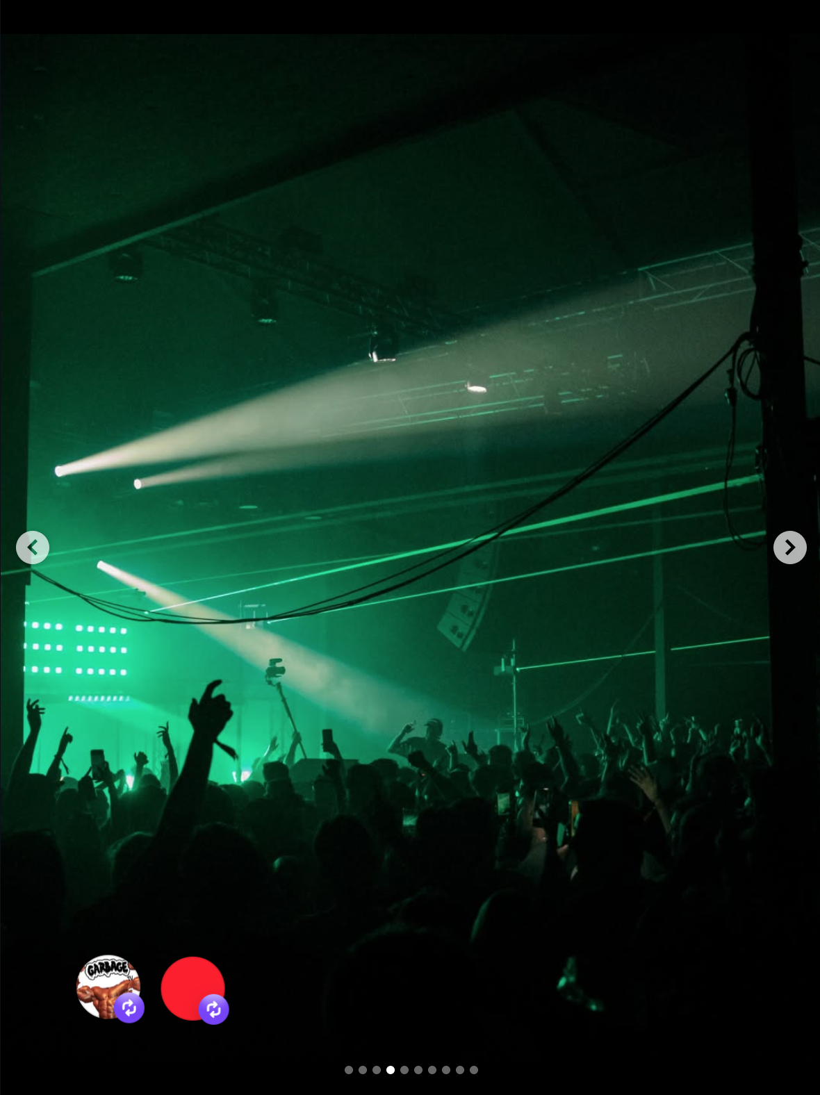 A concert scene with green laser lights, fog effects, and a crowd of people with hands raised, some holding phones, in front of a stage with speakers and lighting equipment.