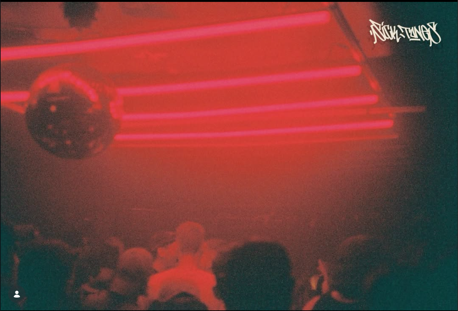 A crowd of people viewing a neon-lit escalator with red and purple lighting, and a graffiti-style logo in the top right corner.