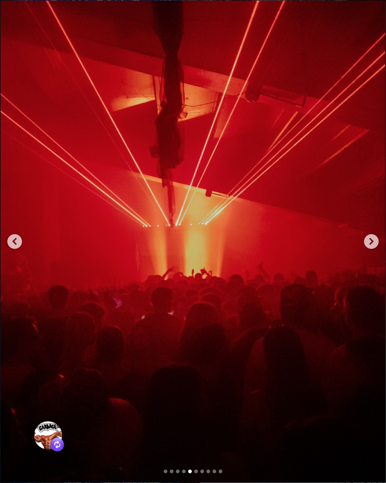 A concert scene with red laser lights, a crowd of people, and a performer on stage with arm raised.