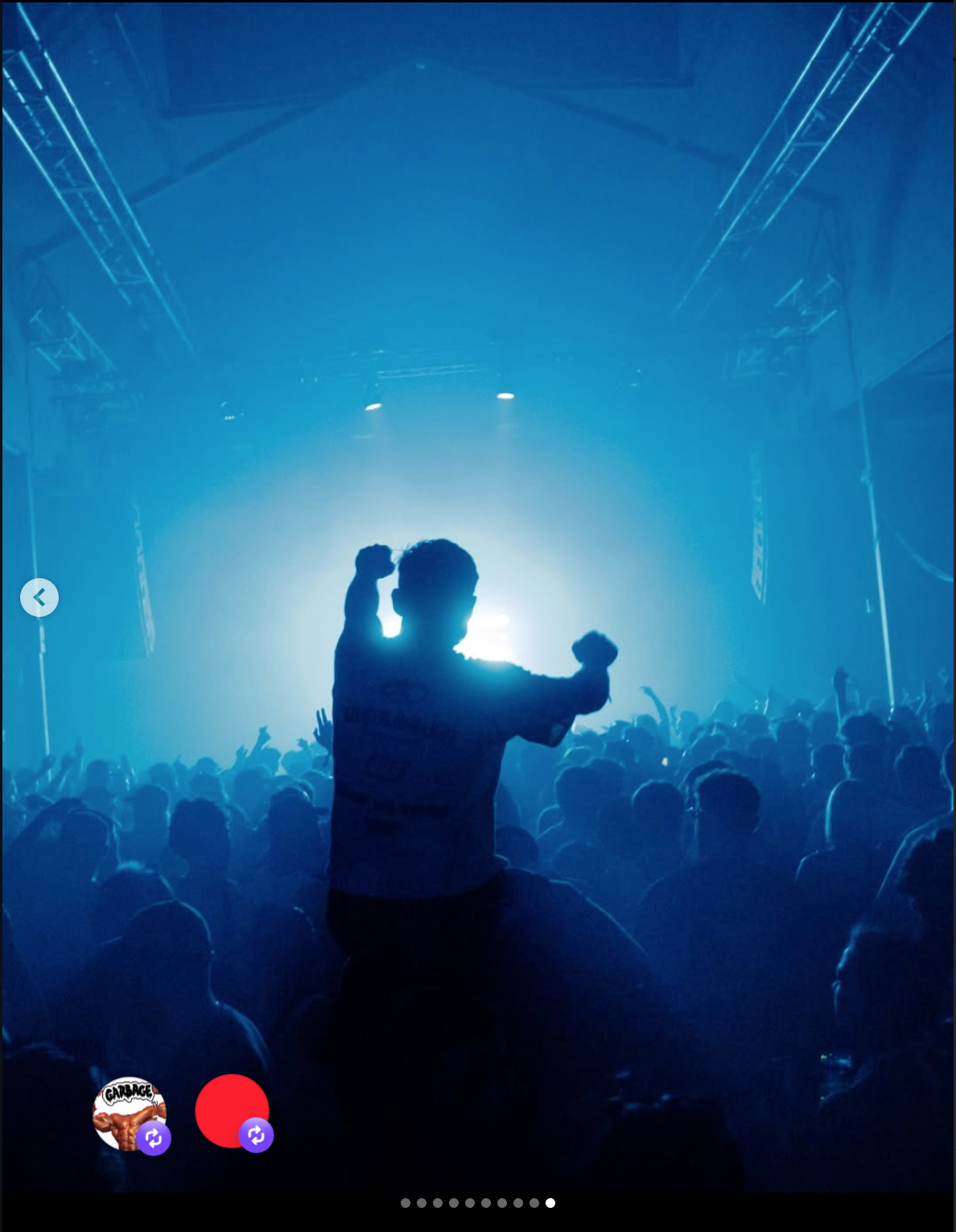 Concert scene with a crowd of people and a silhouetted person on shoulders raising fists, blue stage lighting, and visible stage truss structure.