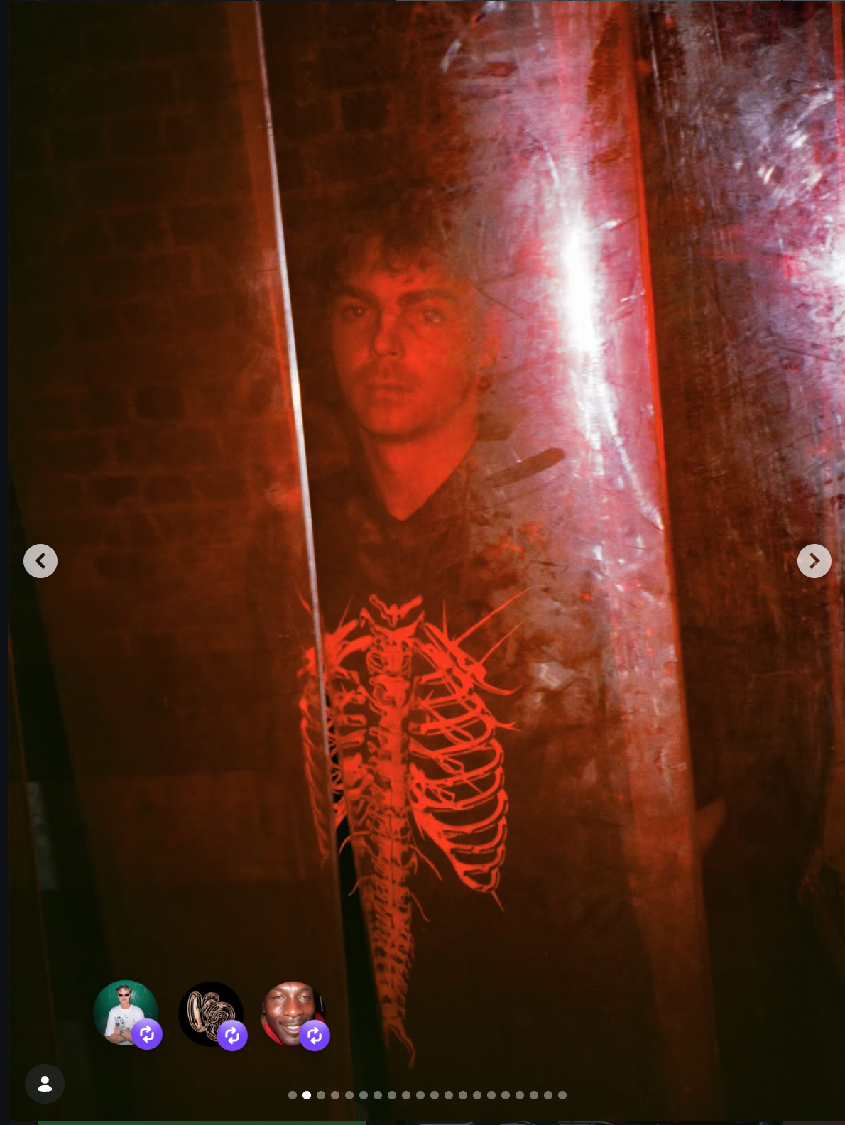 A person with short hair and a serious expression, wearing a black shirt with a red skeleton design, is seen through a red, translucent surface or screen, creating a mysterious effect.