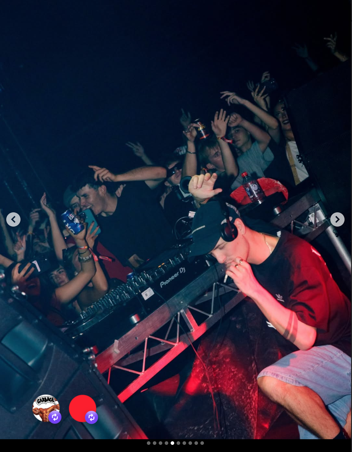 DJ performing at a nightclub with a crowd dancing and raising their hands.