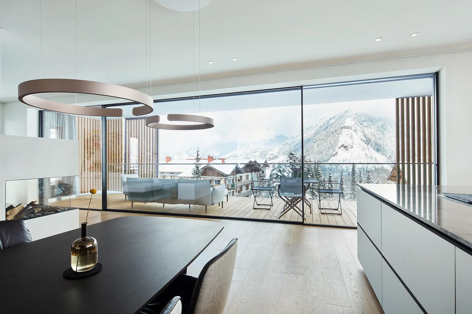 Modern living room with large glass sliding doors leading to a balcony with mountain view, minimalist furniture, and decorative lighting.