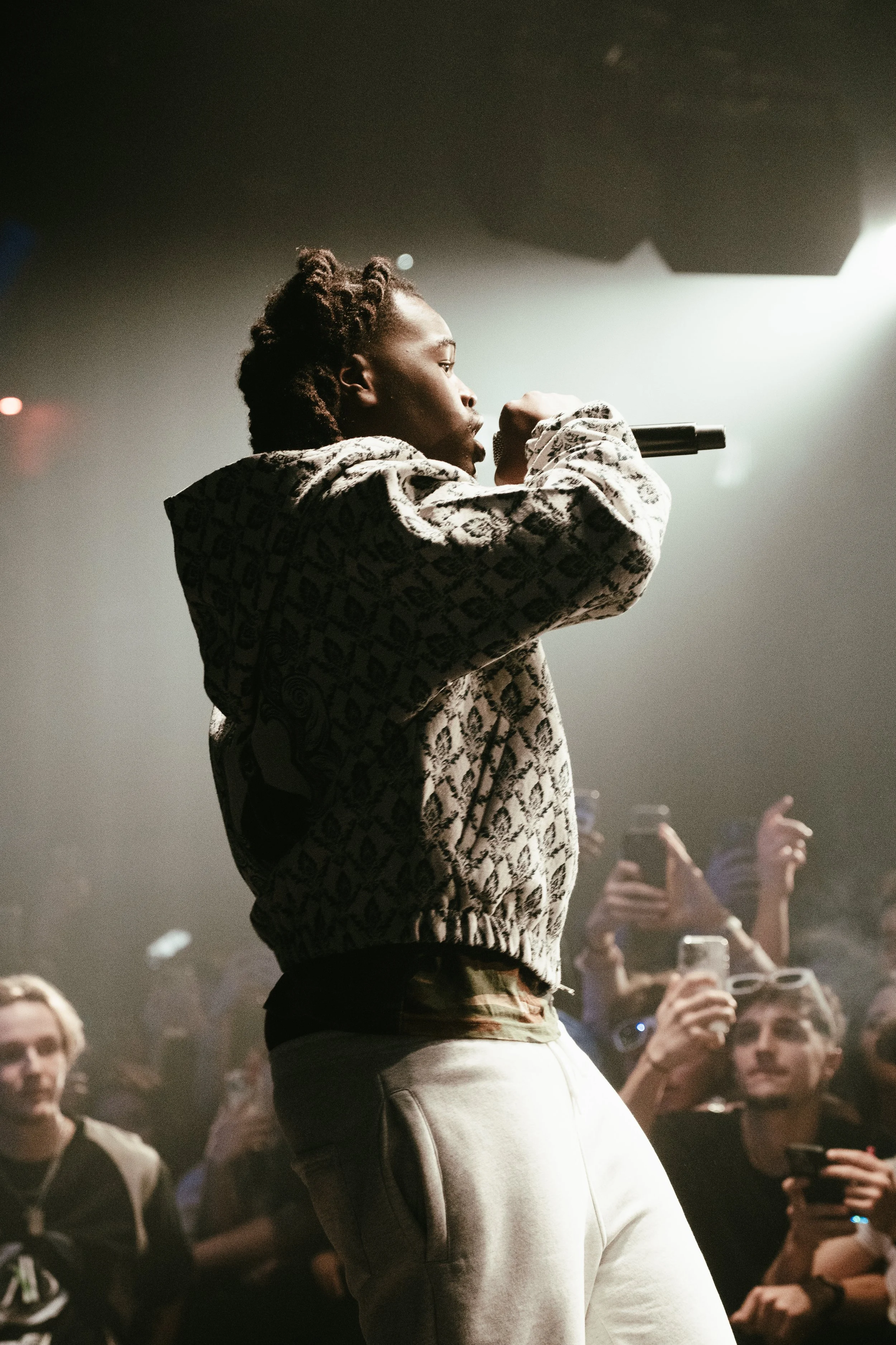 Un artiste en performance avec un micro, entouré d'un public intéressé.