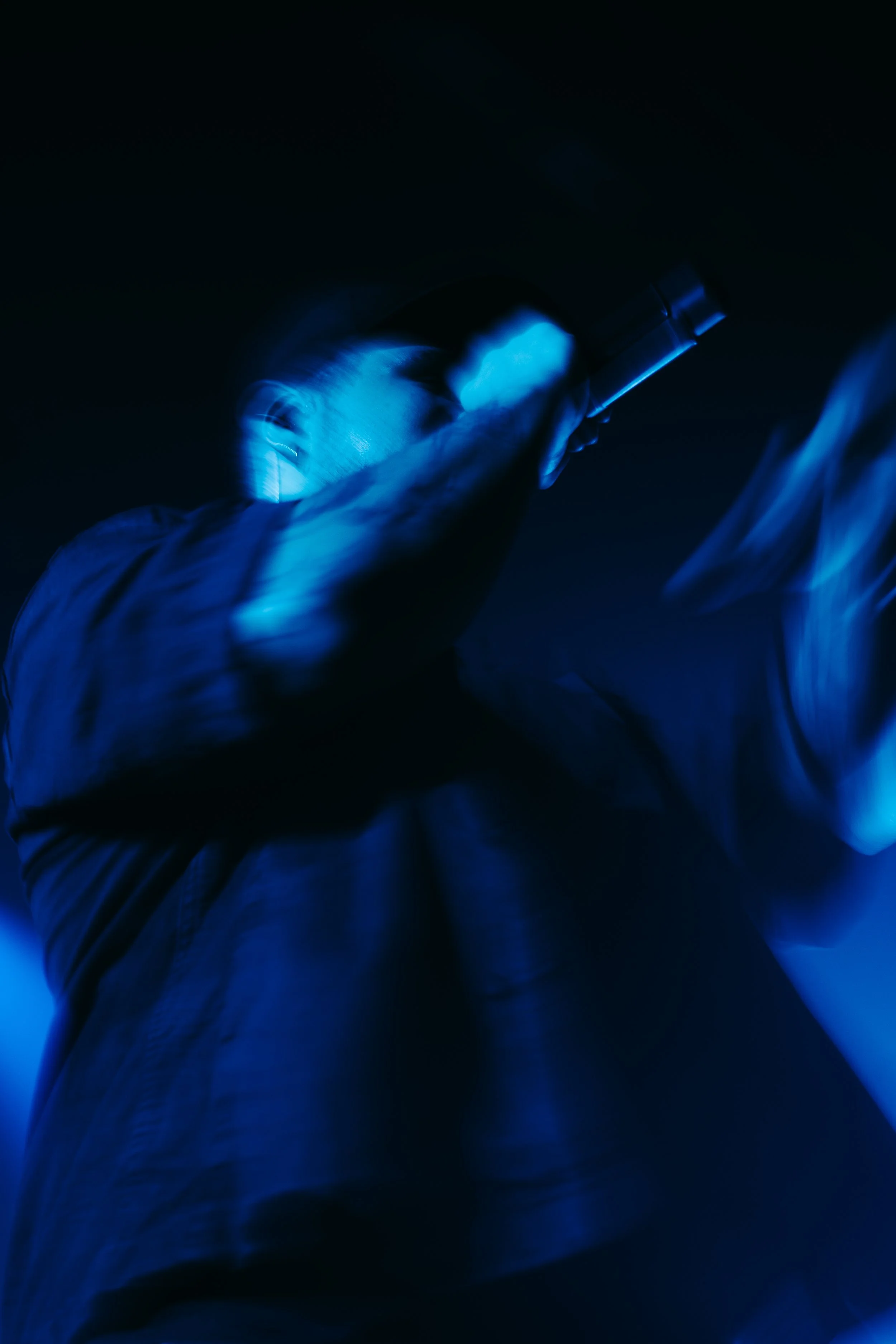 Person observant à travers un télescope dans un environnement sombre, éclairé par une lumière bleue