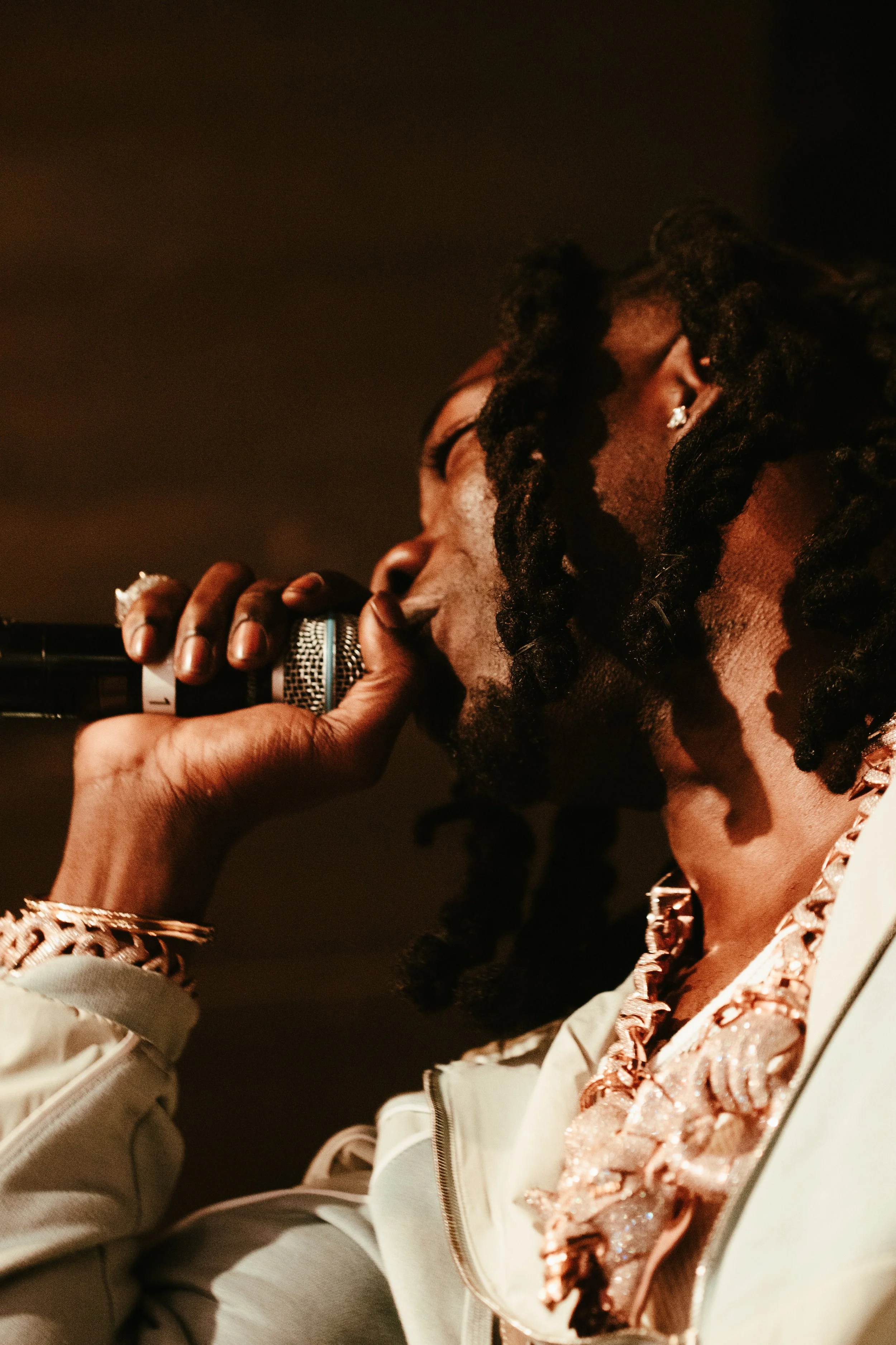 Un homme noir avec des dreadlocks qui chante ou parle dans un microphone.