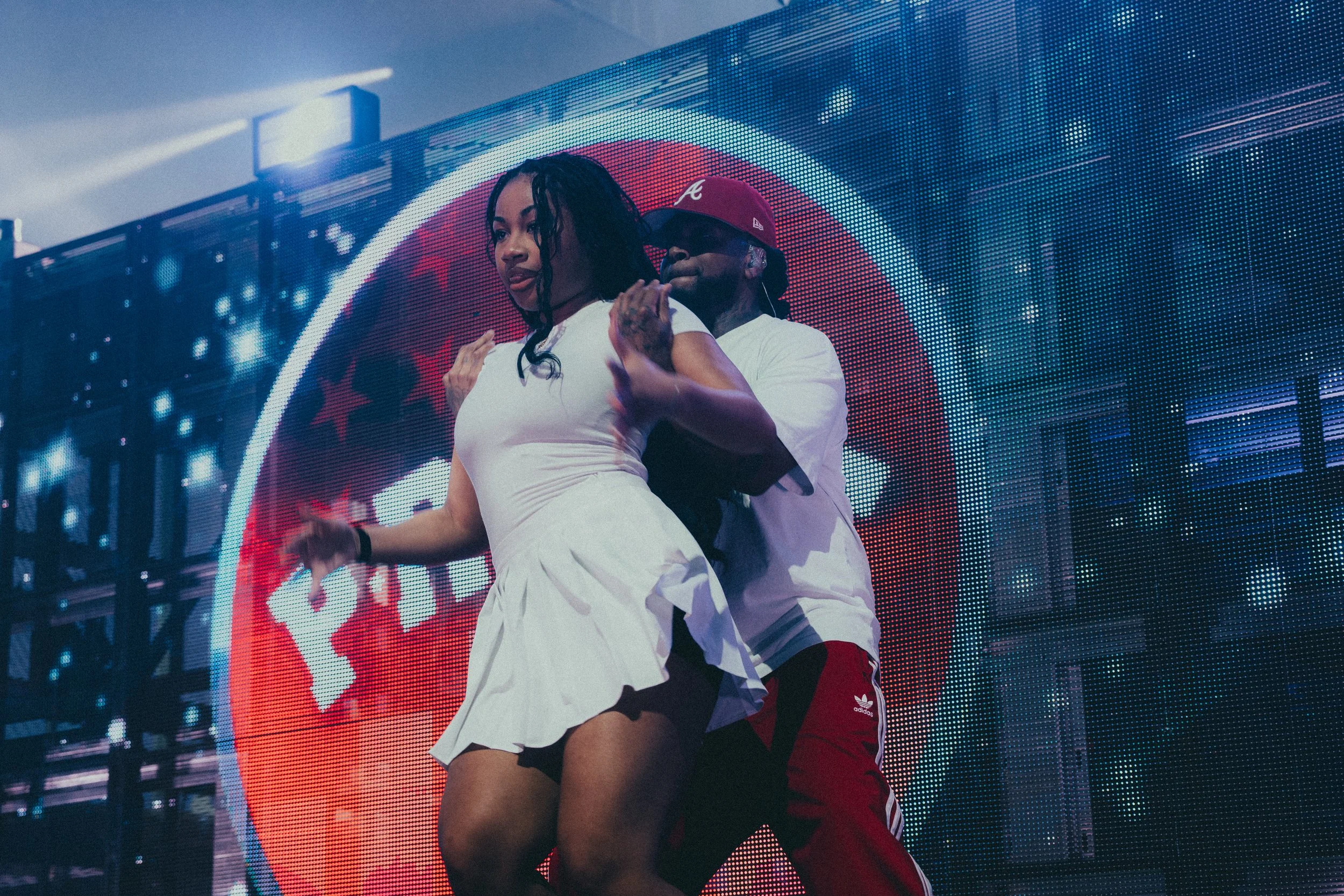 Un homme et une femme dansant lors d'un concert, avec un grand écran lumineux en arrière-plan