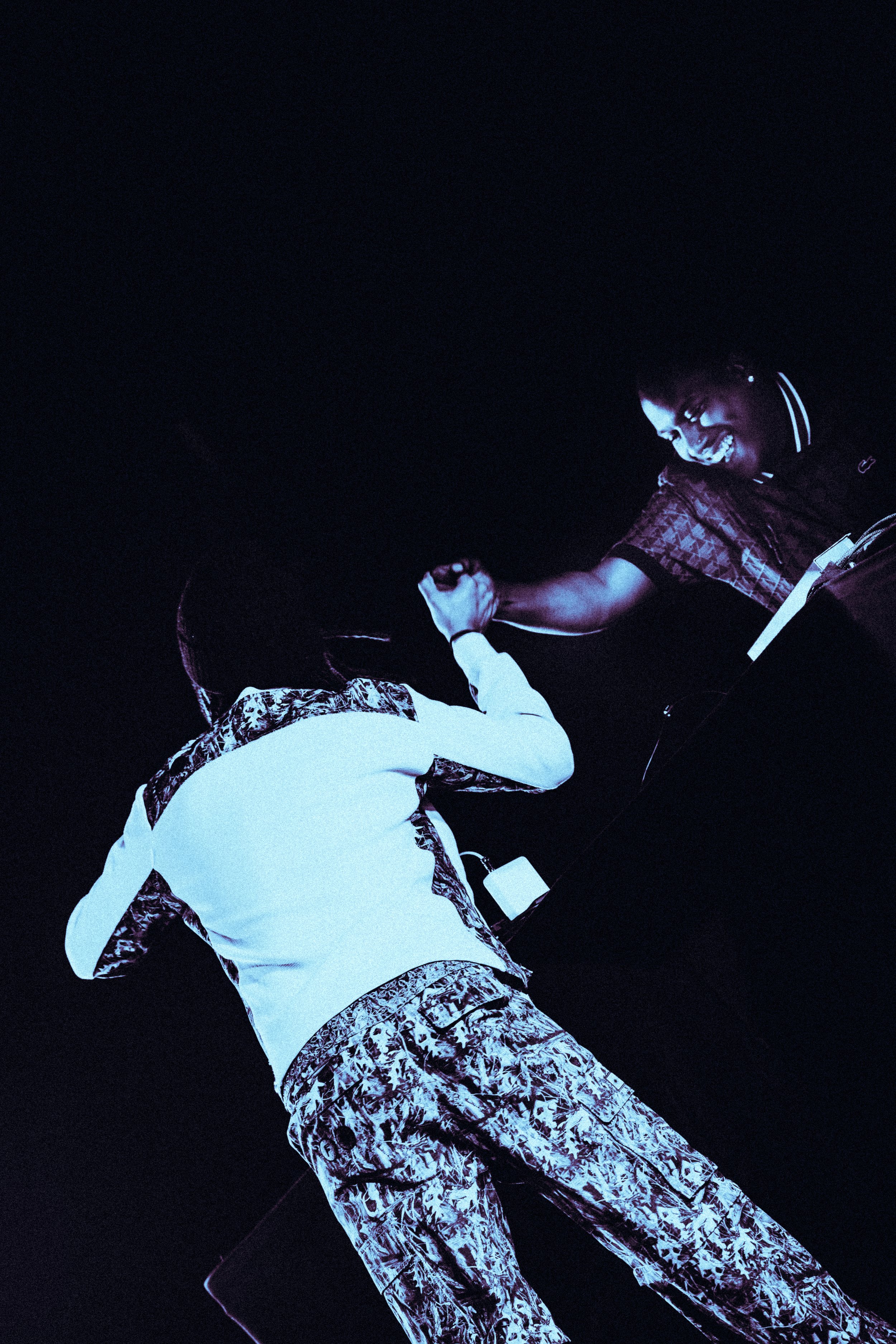 Deux personnes se donnent une poignée de main dans une ambiance sombre avec un éclairage bleu.