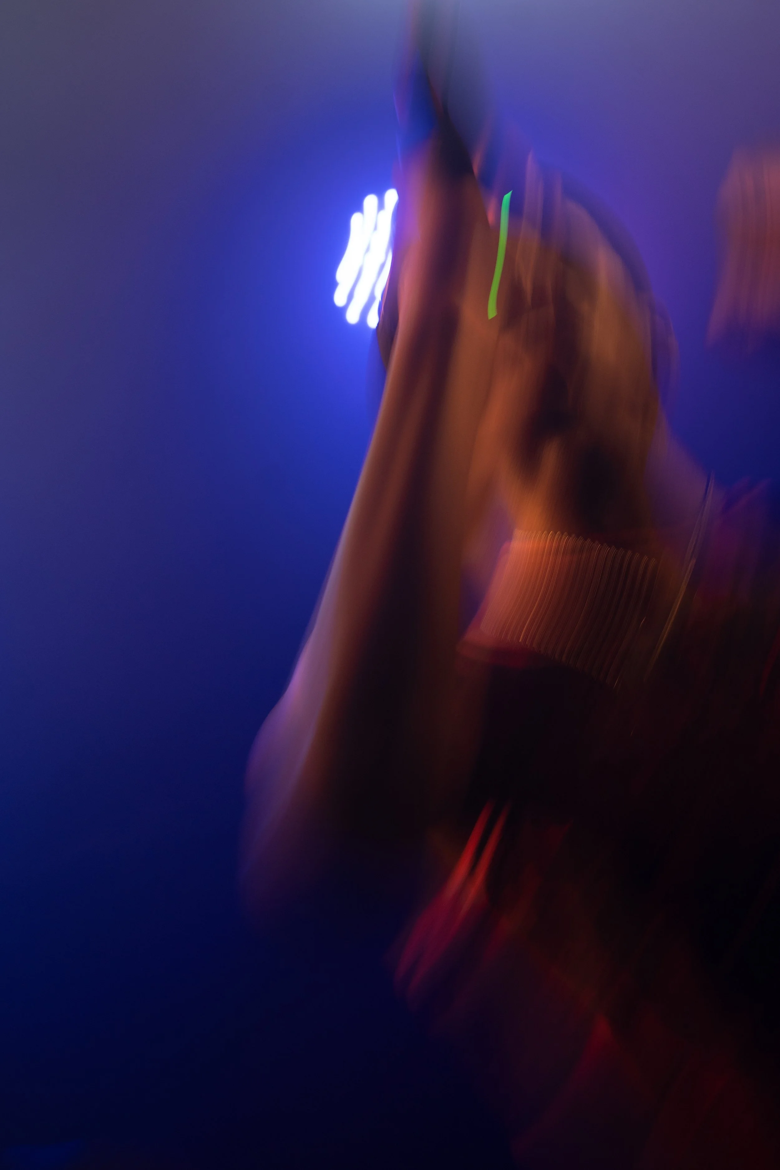 Une personne sous un éclairage violet avec mouvement flou, portant un vêtement avec des détails lumineux.